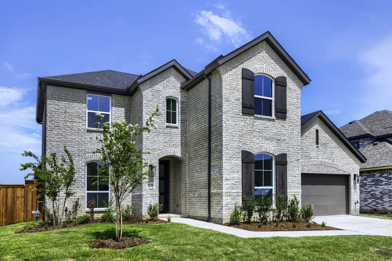 Two-story residence featuring light-colored brick facade and a dark shingle roof