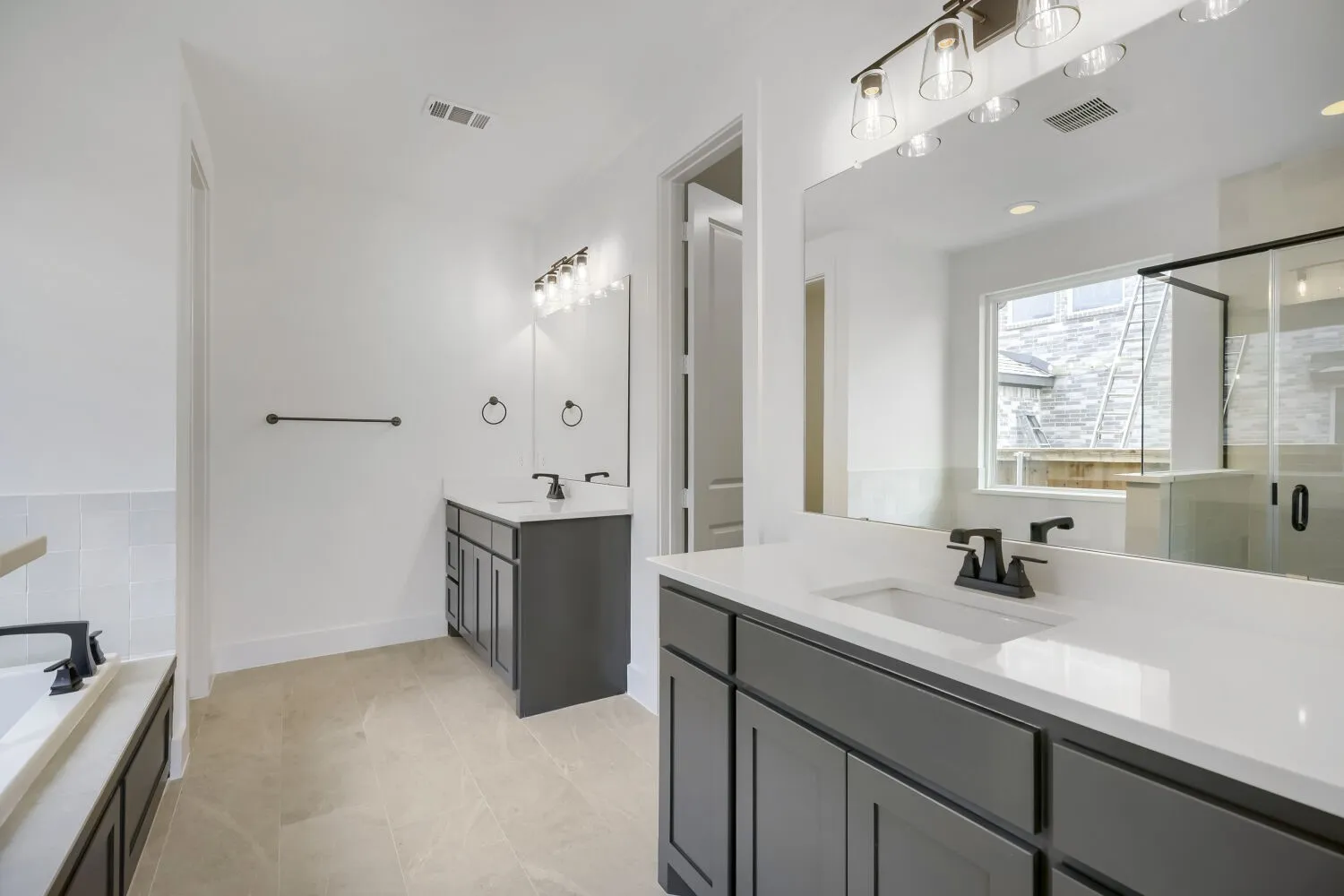 Dual vanity setup featuring white countertops and dark cabinetry, complemented by matte black fixtures