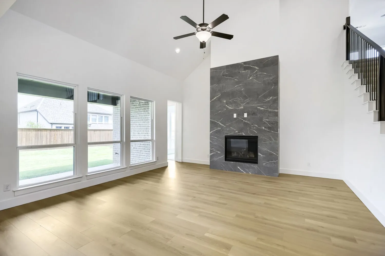 Vaulted ceiling with an overhead fan, featuring wood-finish flooring