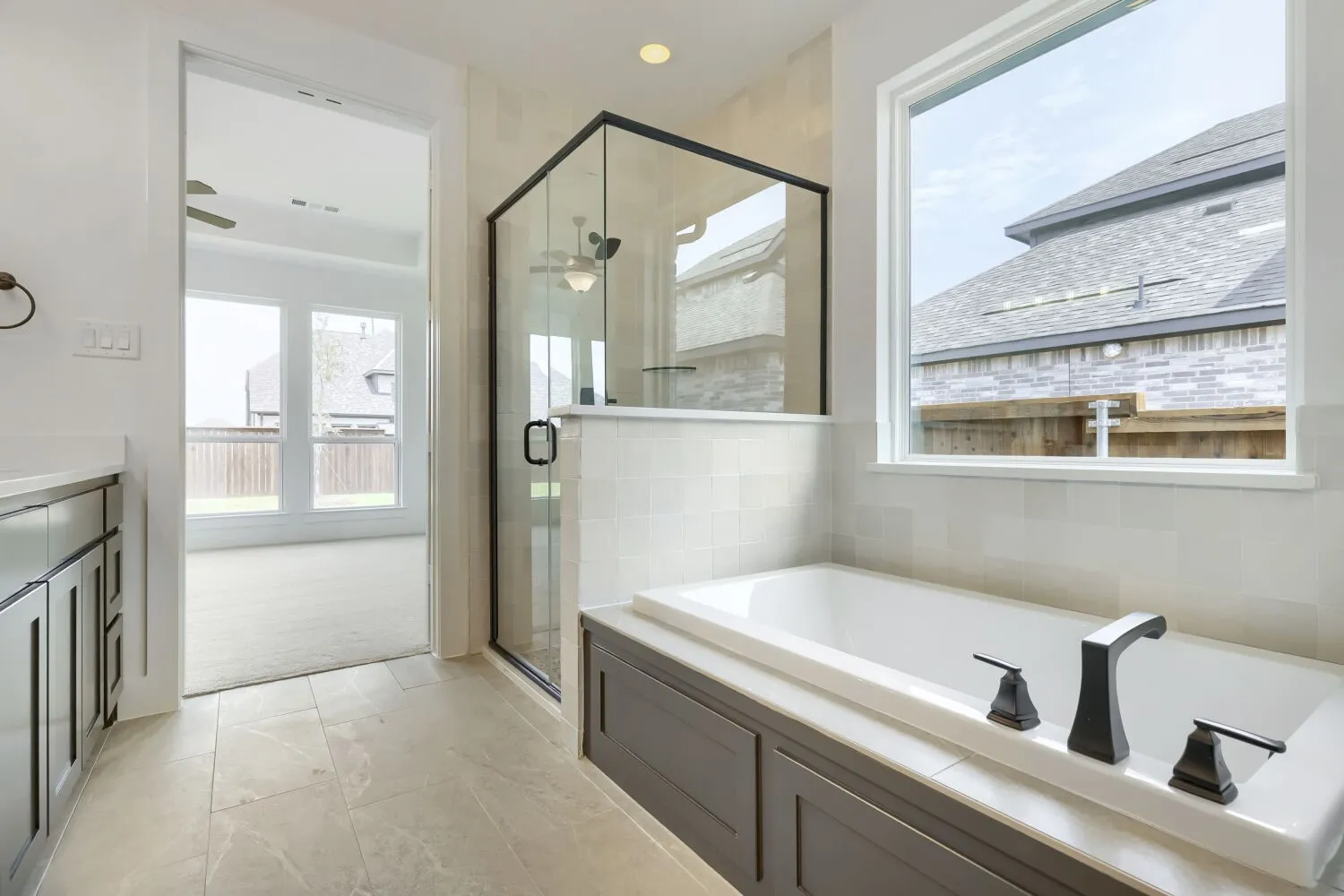 Bathroom featuring a built-in soaking tub with dark-toned fixtures, a walk-in shower with black-framed glass enclosure, and a vanity with dark cabinetry
