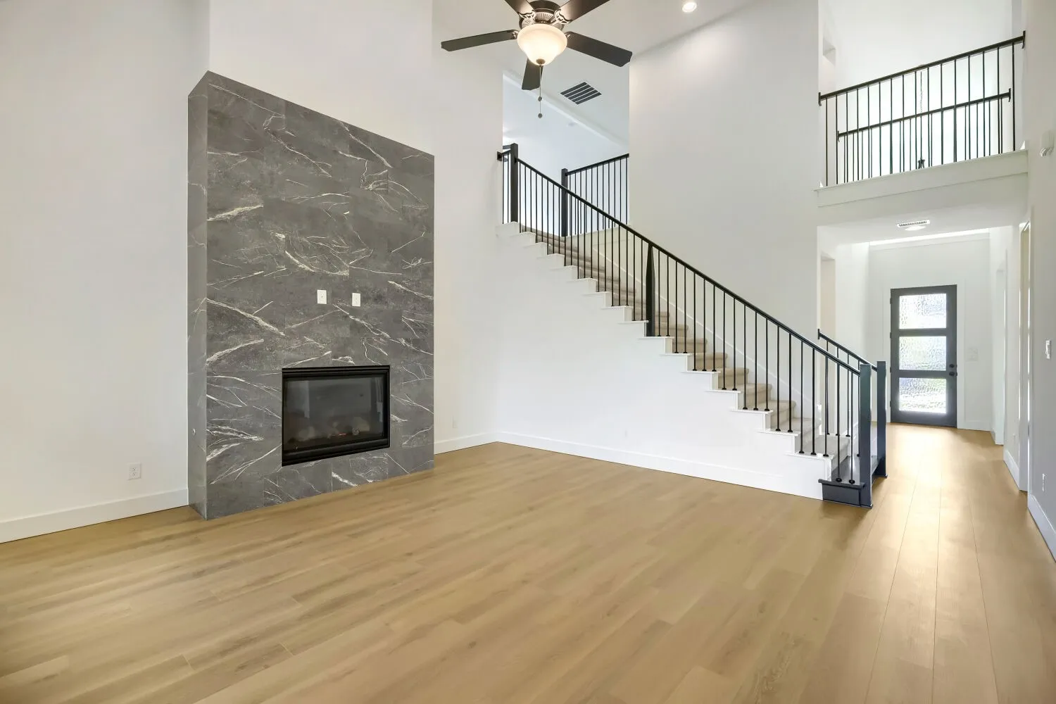 Two-story interior featuring a grand fireplace with a dark, veined stone finish