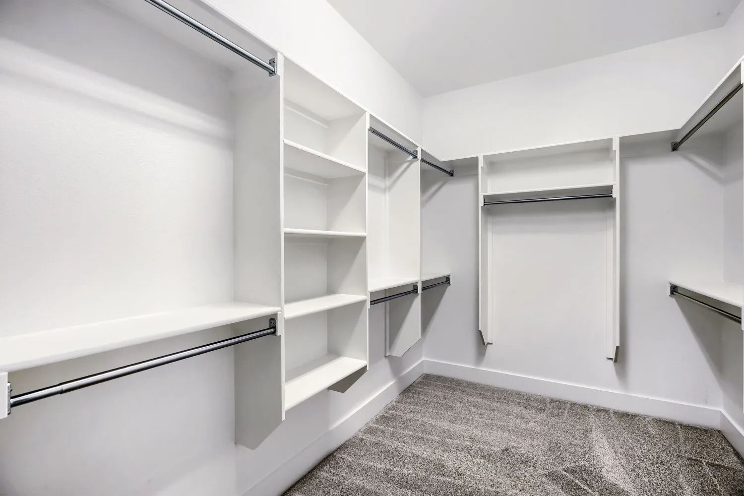 Walk-in closet featuring built-in shelving, multiple hanging rods, white trim, and patterned carpeting