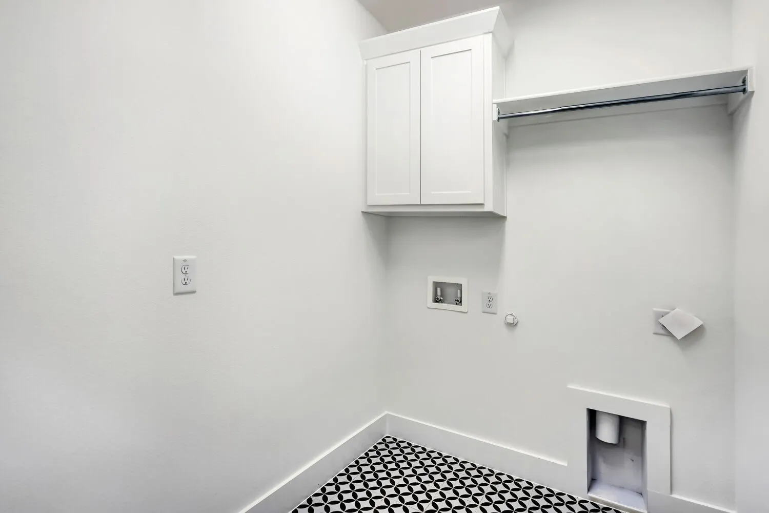 Laundry room featuring patterned floor tiling, crisp white walls, built-in cabinetry, and a clothing rod