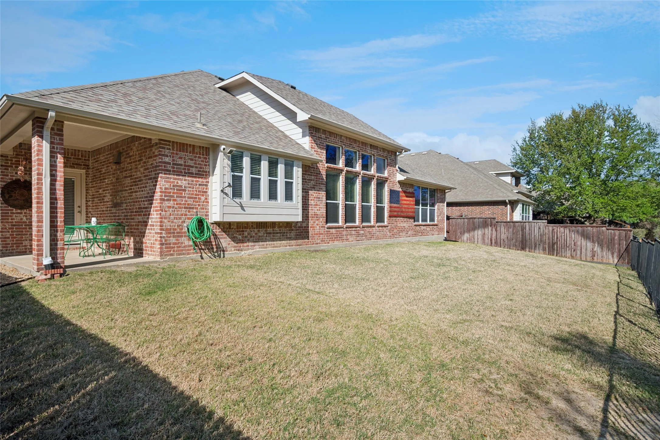 Covered patio off kitchen area - backyard views the Shores park.  Iron fence with gate access to park