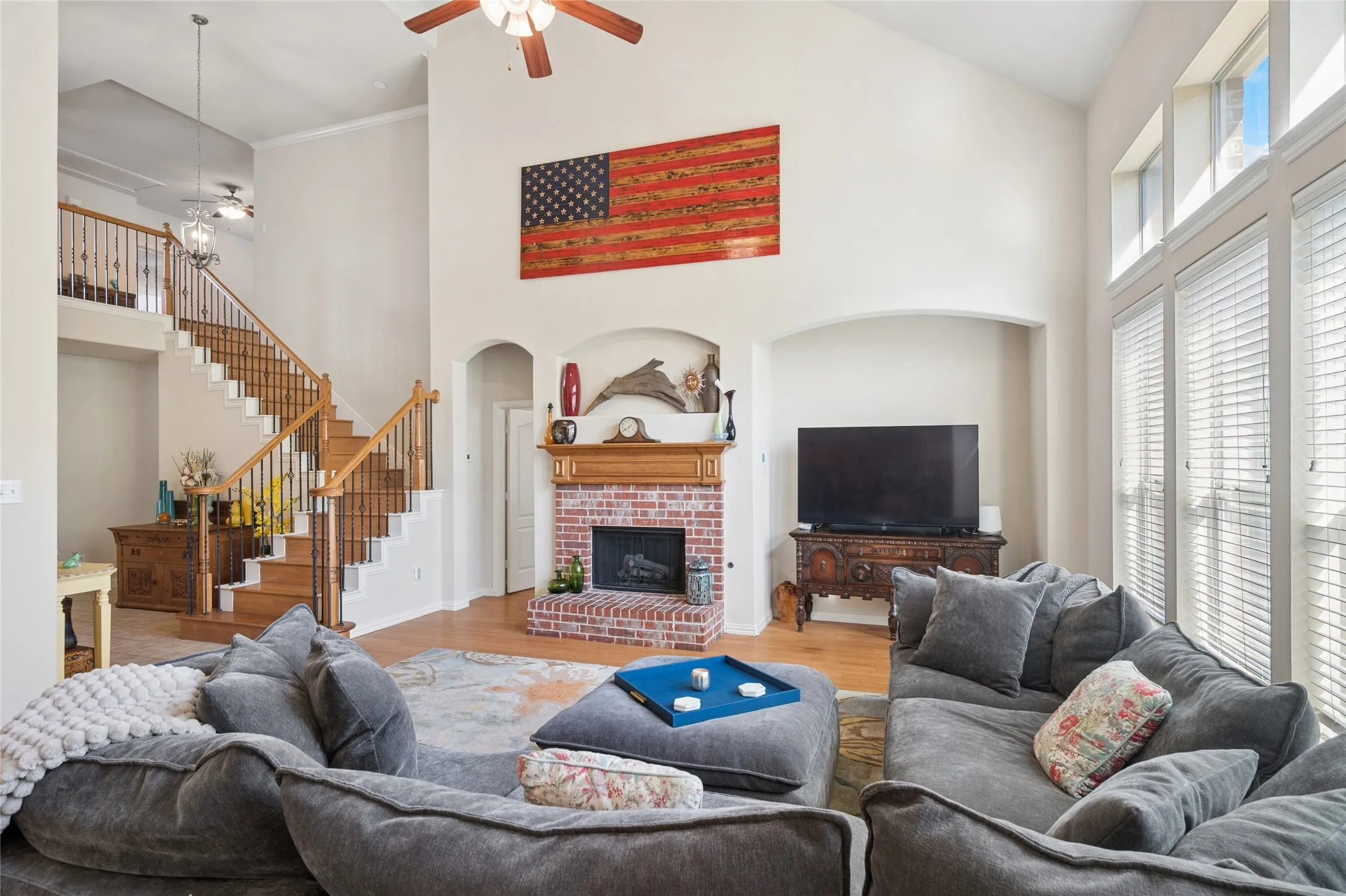 Living room with soaring ceilings , wall of windows provides natural light.  Brick fireplace with gas logs