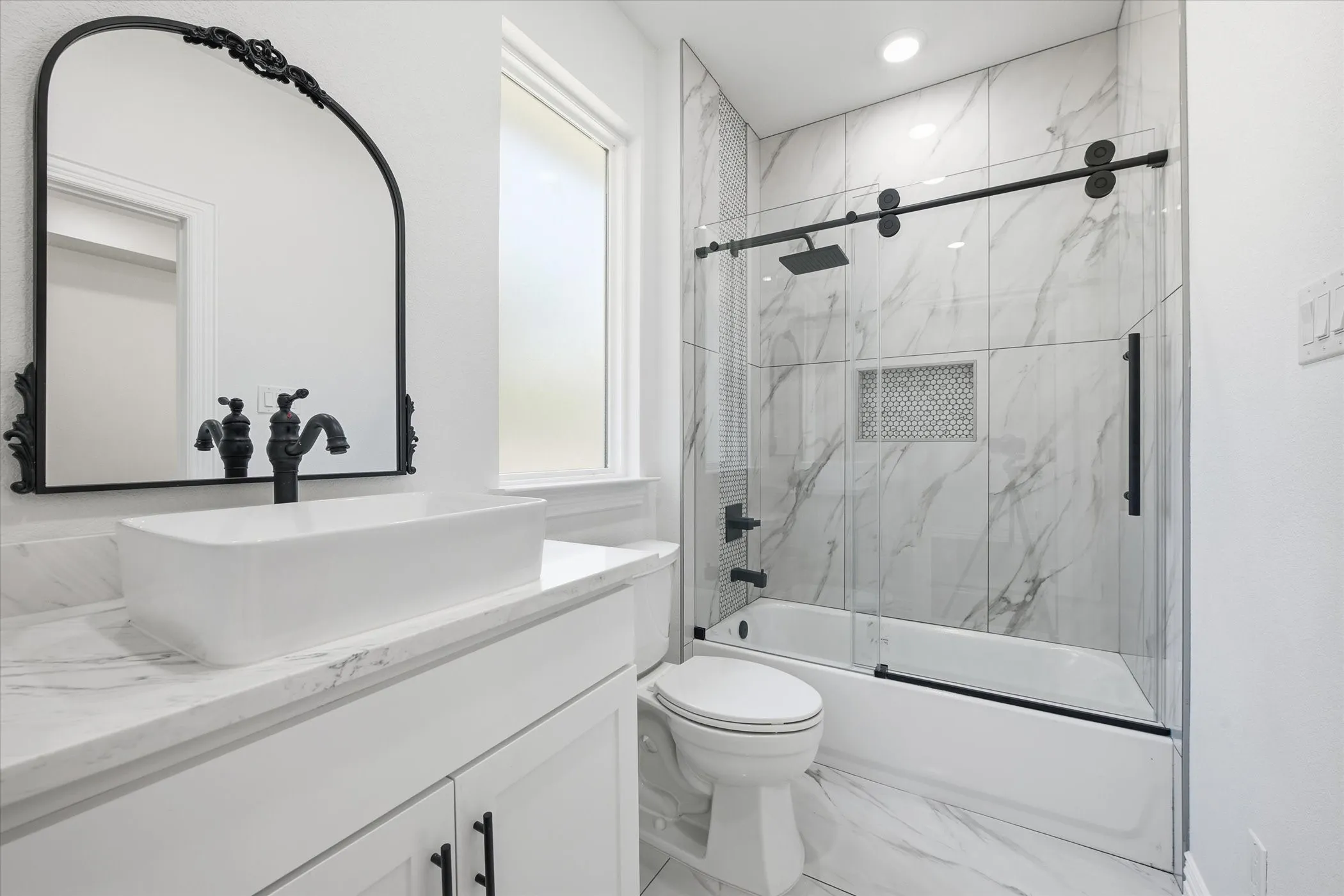 Full bath featuring vanity, bath / shower combo with glass door, and marble look tiles