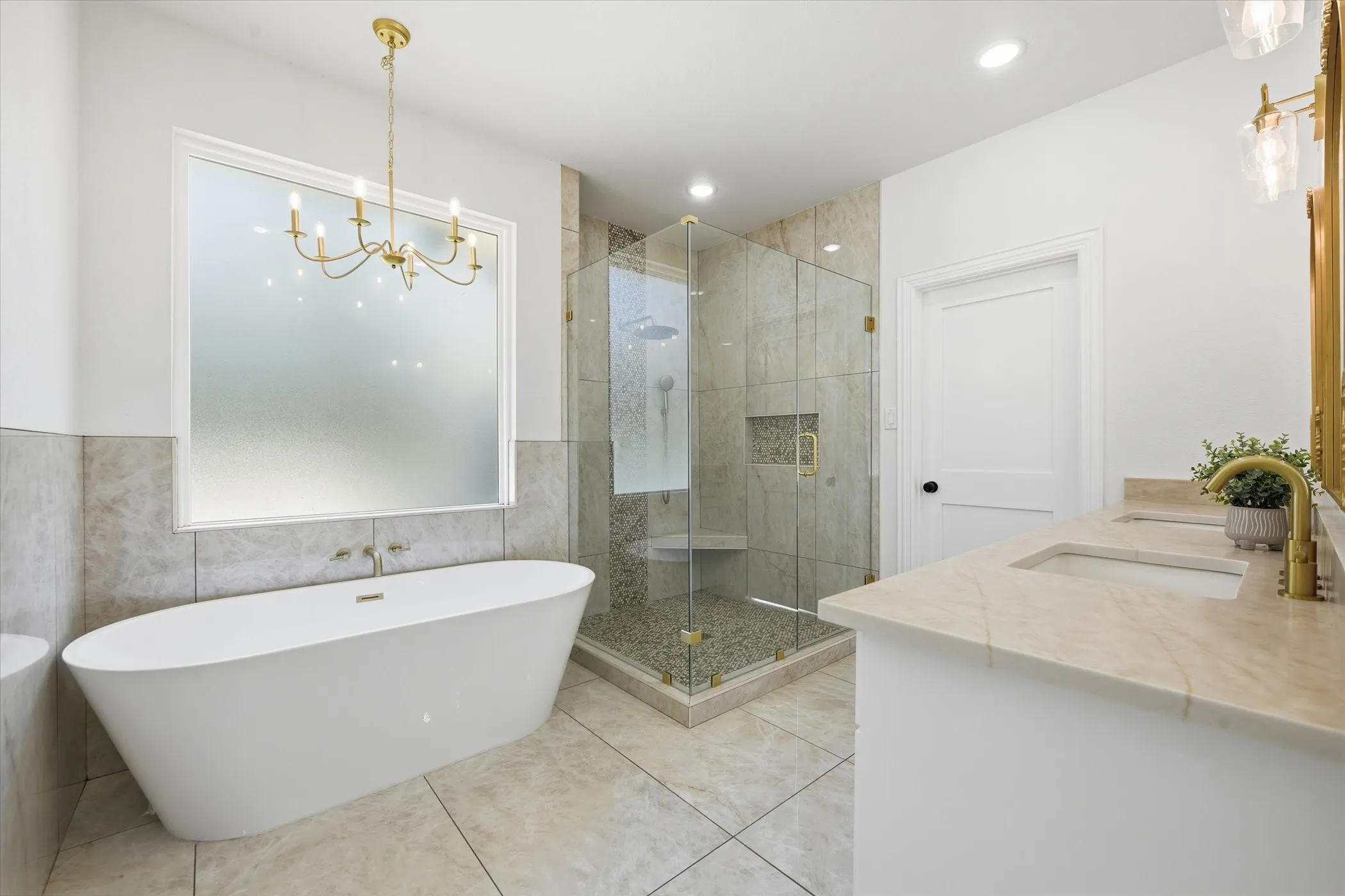 Full bathroom featuring a soaking tub, a stall shower, double vanity, tile walls, and suspended lighting
