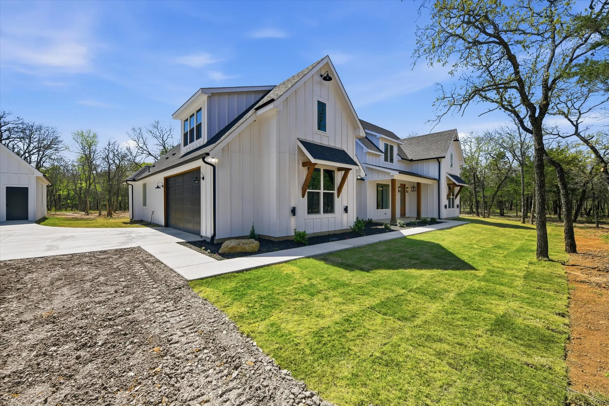 Modern inspired farmhouse with board and batten siding, driveway, a front lawn, and covered porch