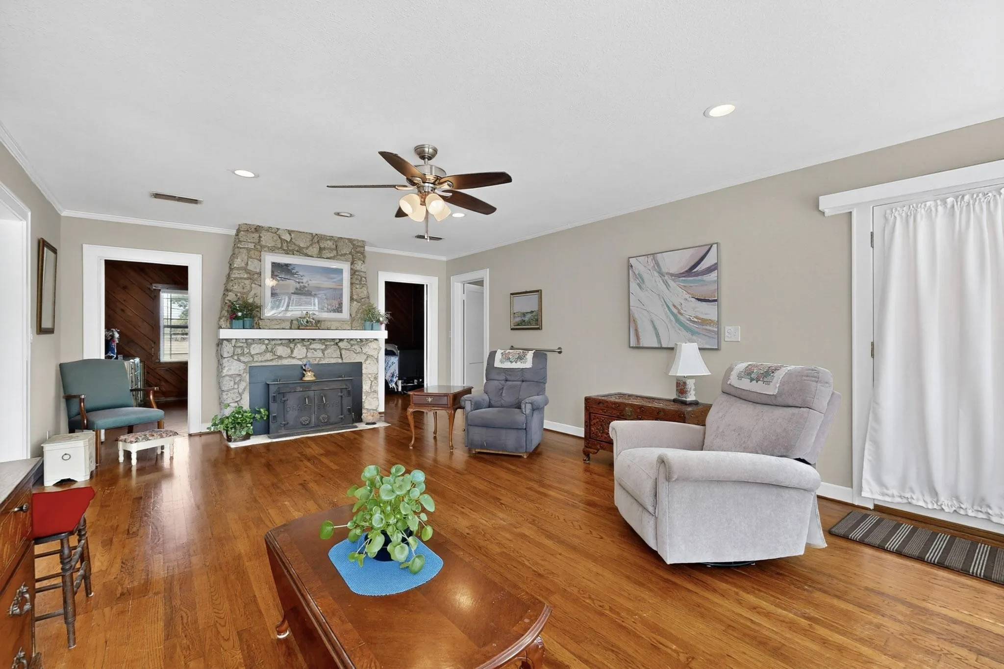 Living room with wood finished floors, ceiling fan, ornamental molding, and recessed lighting
