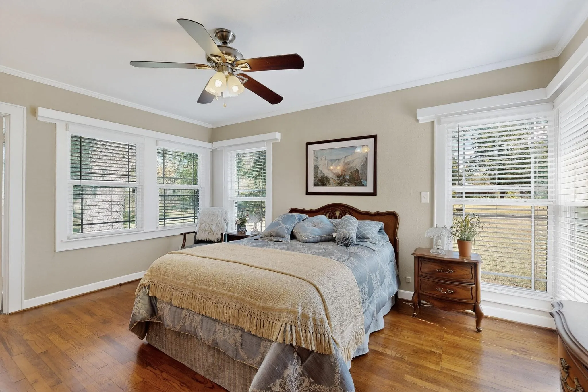 Bedroom featuring crown molding, multiple windows, wood finished floors, and ceiling fan