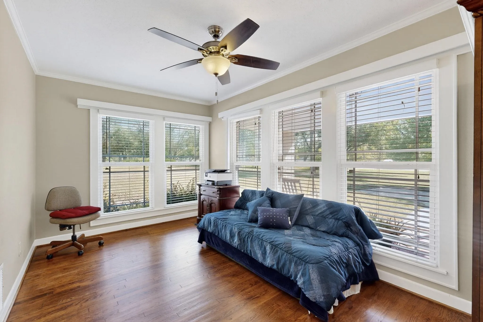 Sitting room featuring wood finished floors, crown molding, and a ceiling fan
