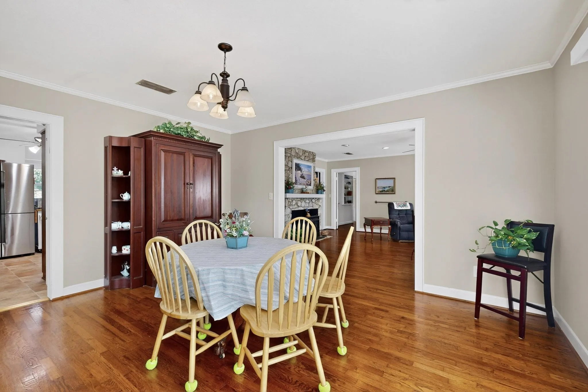 Dining room featuring light wood-style floors, crown molding, a fireplace, and a chandelier