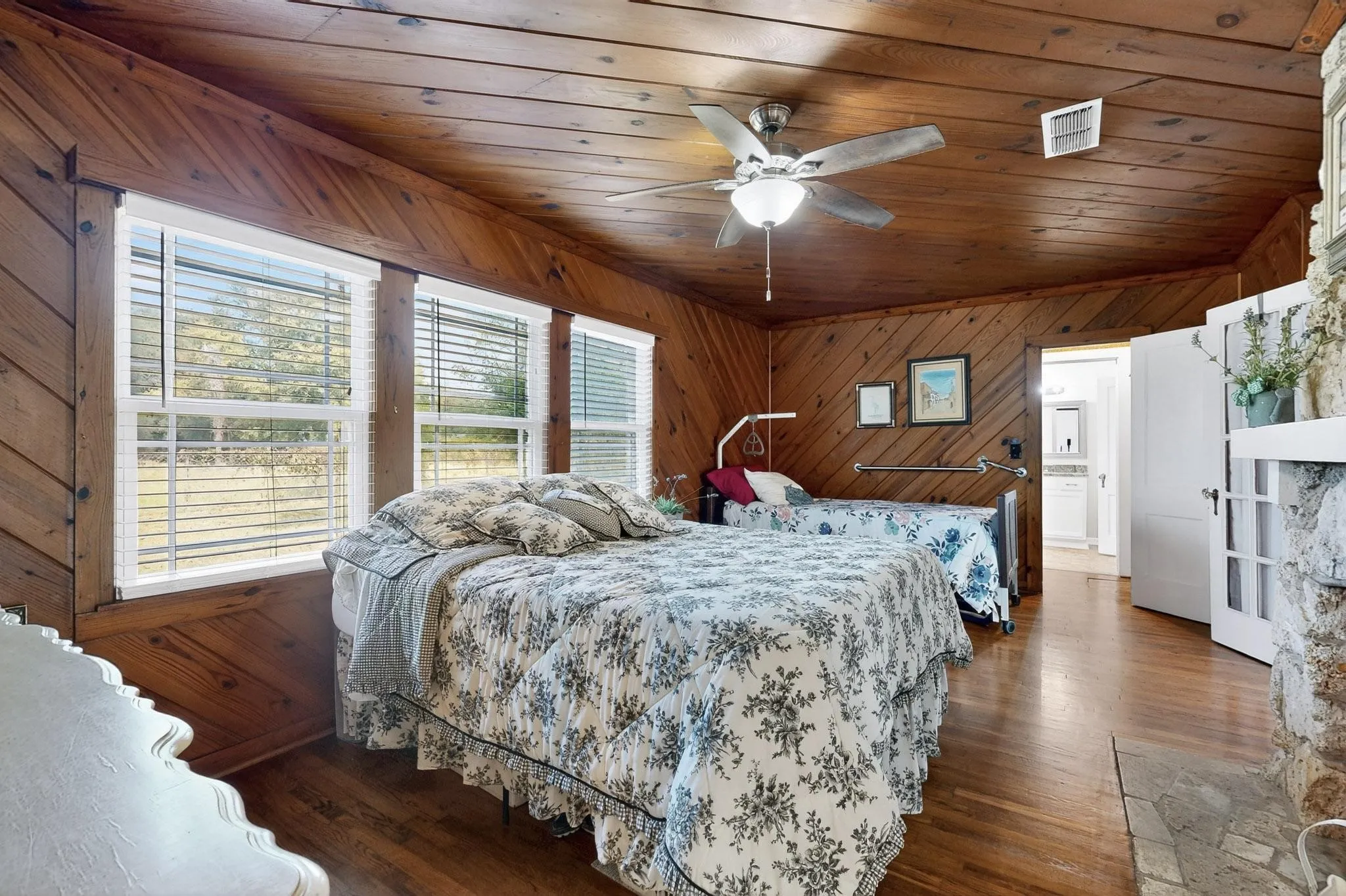 Bedroom featuring wood walls, wood ceiling, a ceiling fan, and wood finished floors