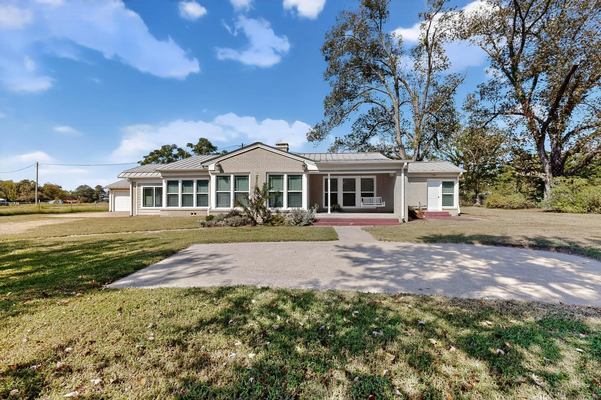 Ranch-style home featuring a metal roof, a standing seam roof, brick siding, and a front lawn