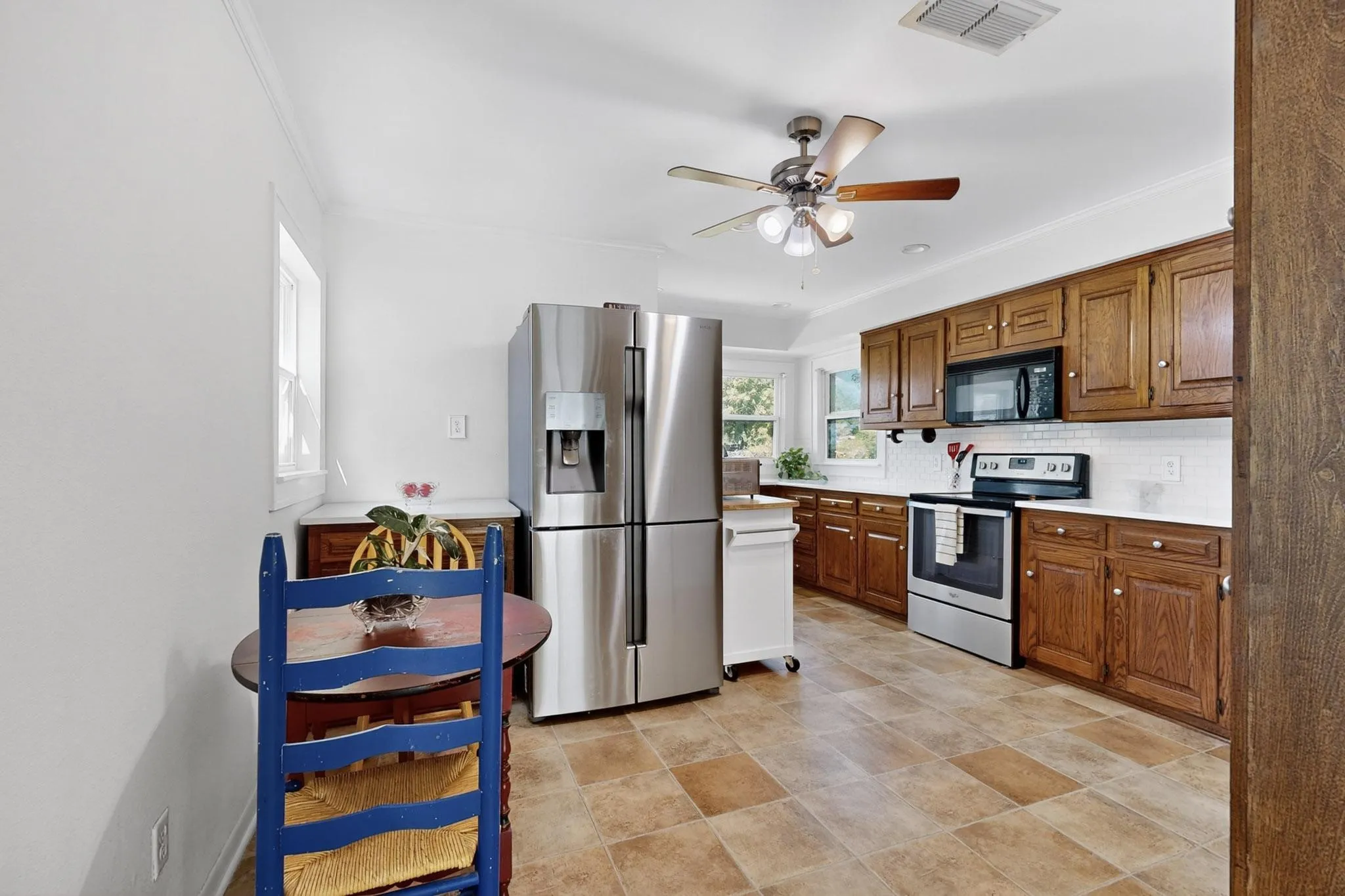 Kitchen featuring light countertops, appliances with stainless steel finishes, brown cabinetry, tasteful backsplash, and ceiling fan
