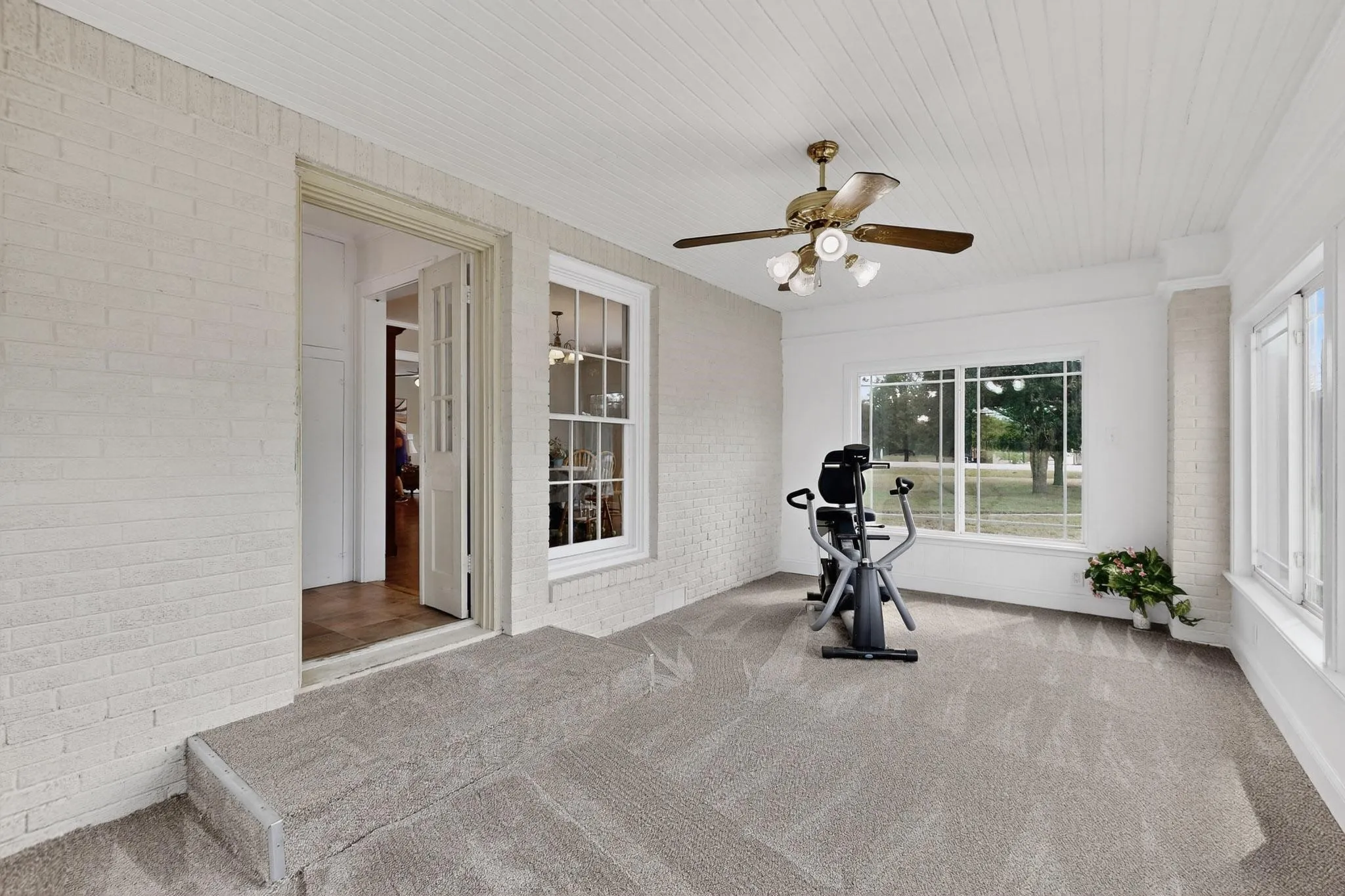 Exercise room with brick wall, carpet floors, ceiling fan, and wood ceiling