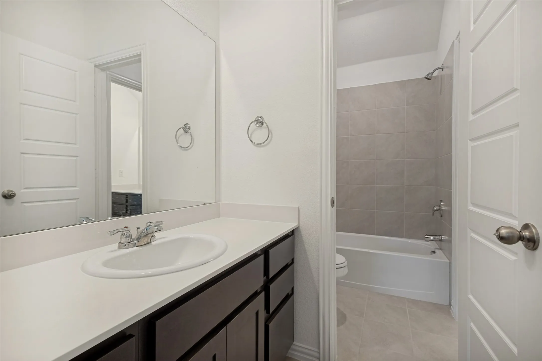 Bathroom vanity featuring a white countertop with an undermount sink and dark wood-finish cabinetry