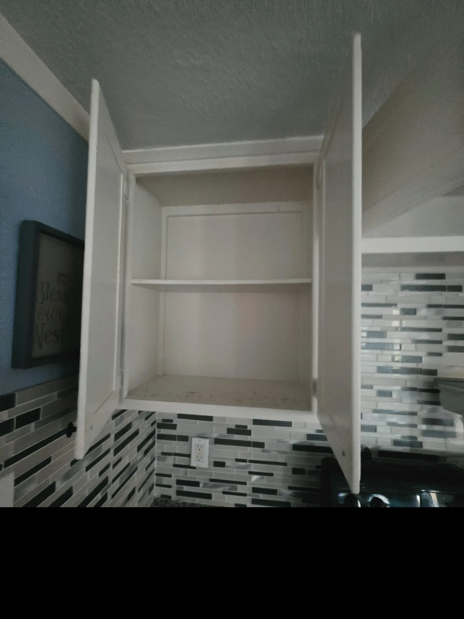 White upper cabinetry with open shelving, complemented by a contemporary mosaic tile backsplash in varying shades of grey and black