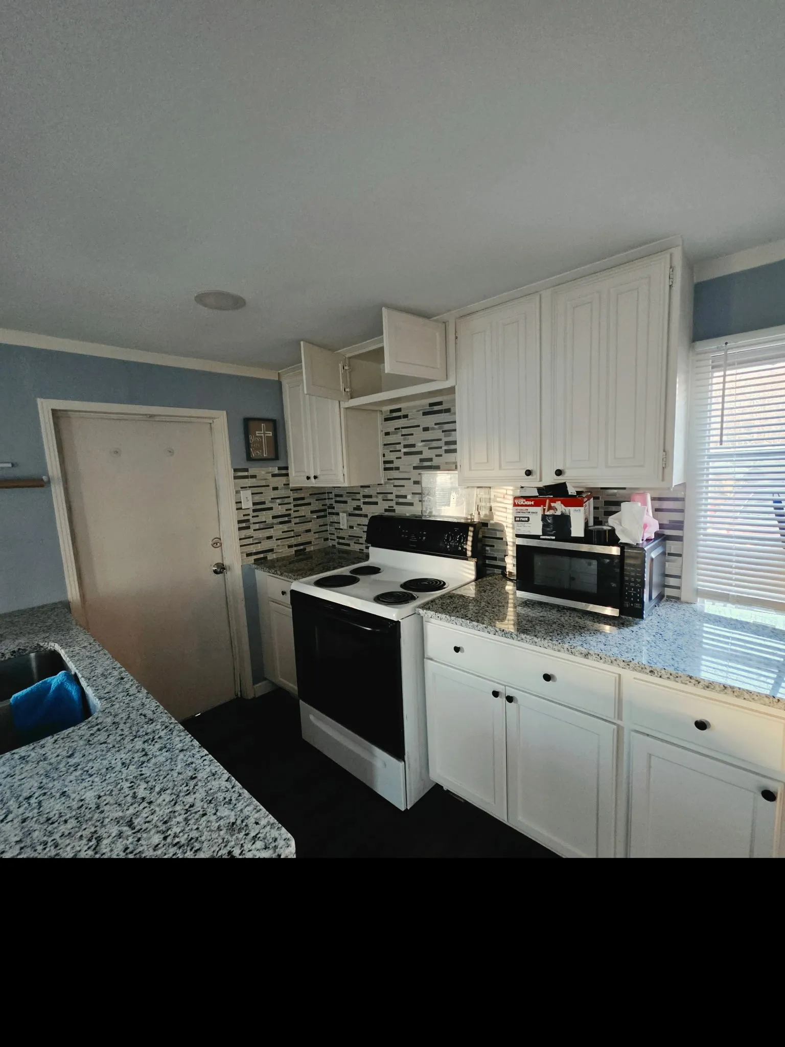 Kitchen featuring white cabinetry, speckled countertops, a tile backsplash, and a built-in oven with a stovetop