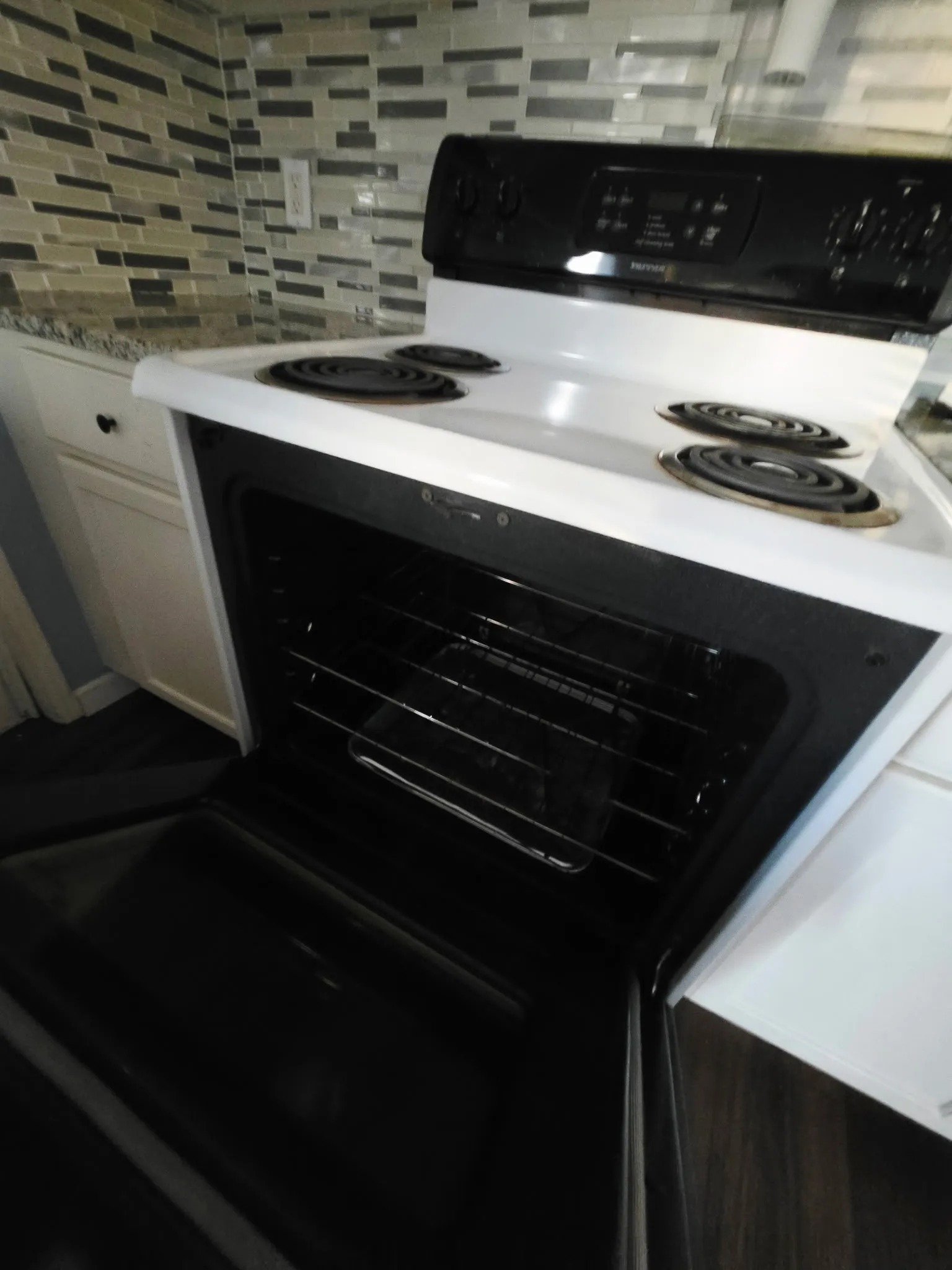 White electric range with black burner coils, a digital control panel, and a visible oven interior