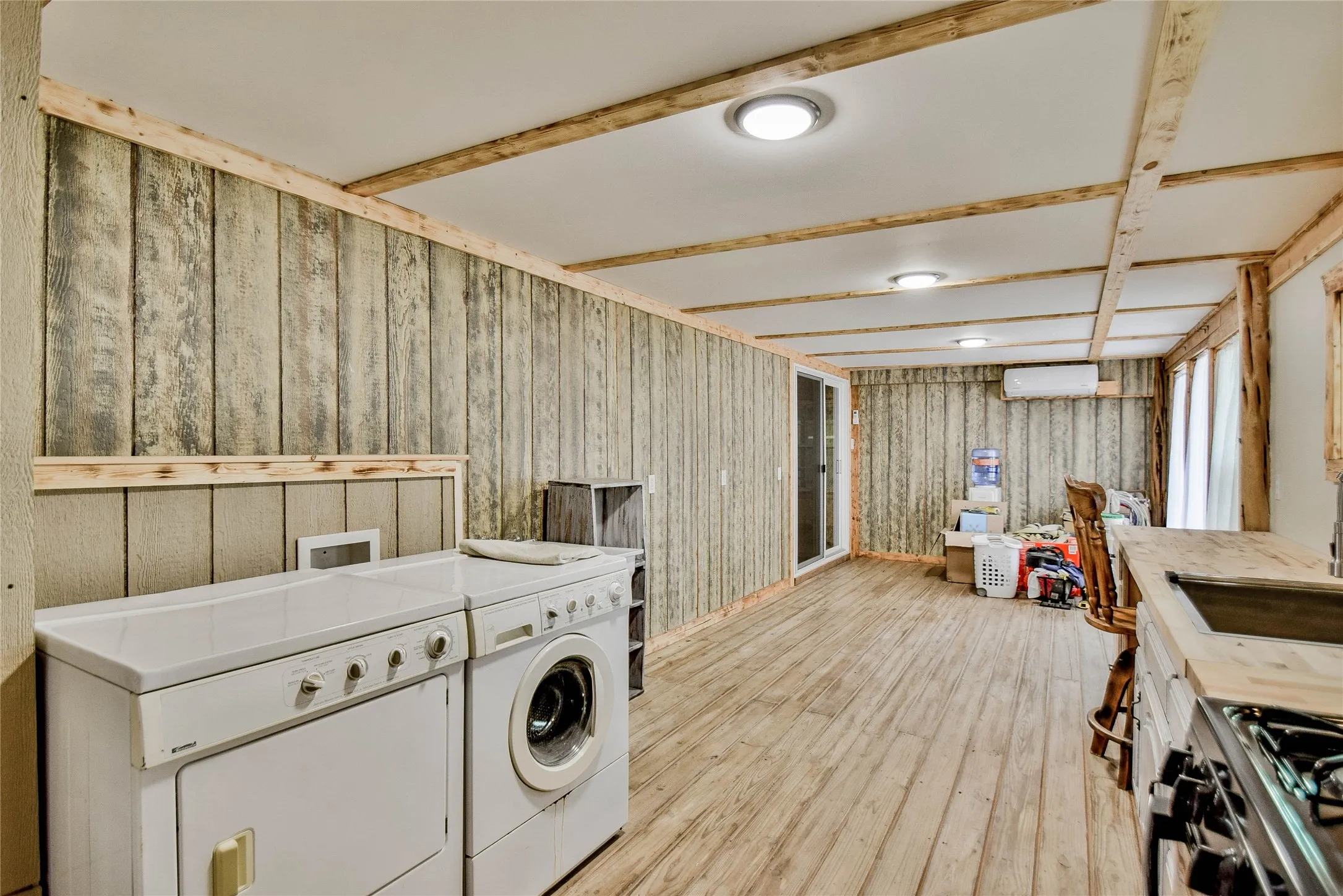 Laundry area featuring wood walls, washing machine and dryer, and light wood-style floors - plenty of room for children's play room, craft room or home office!