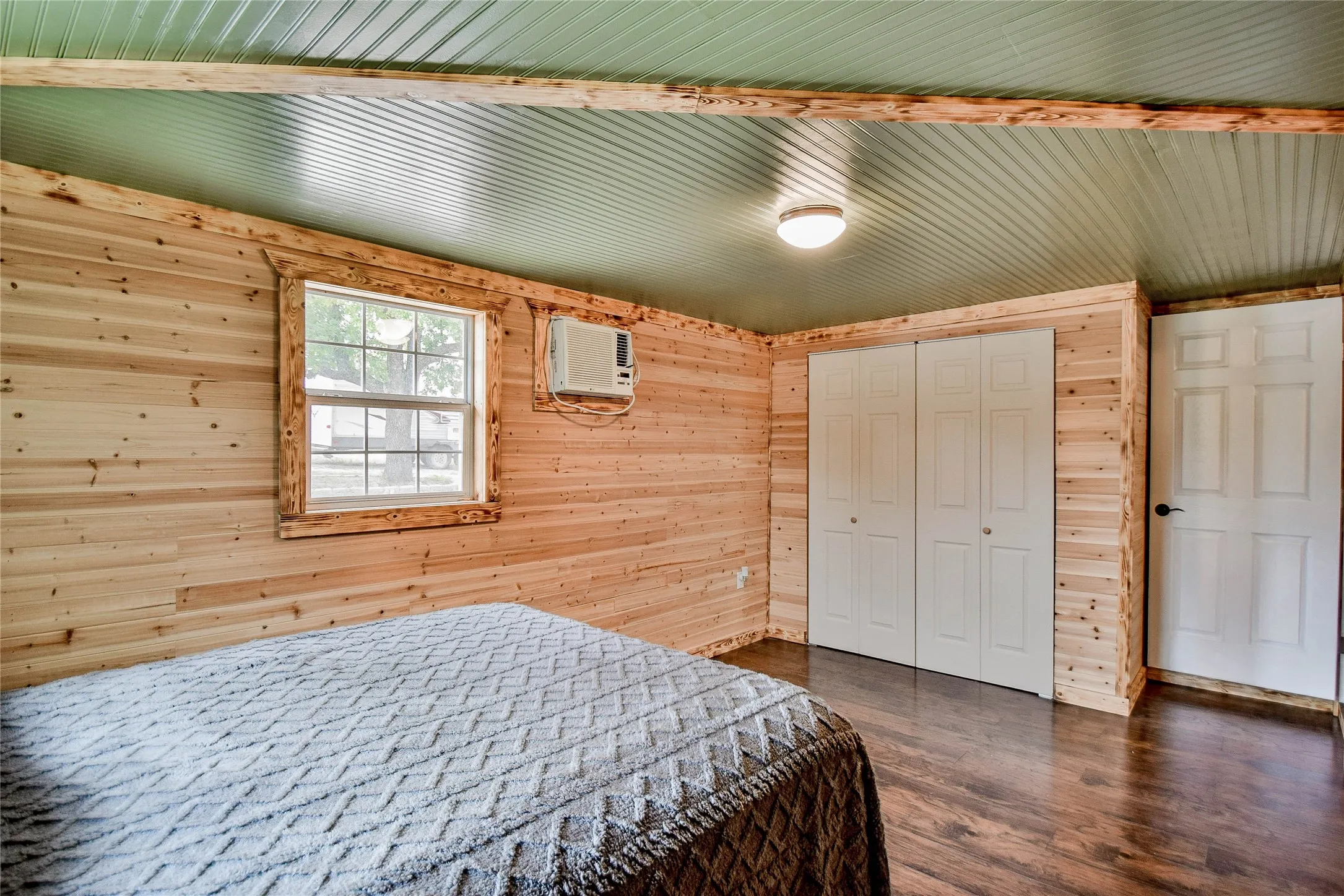 Front Guest bedroom with wood walls, wooden ceiling, wood-style flooring, and a roomy closet will please your guests for privacy and comfort.