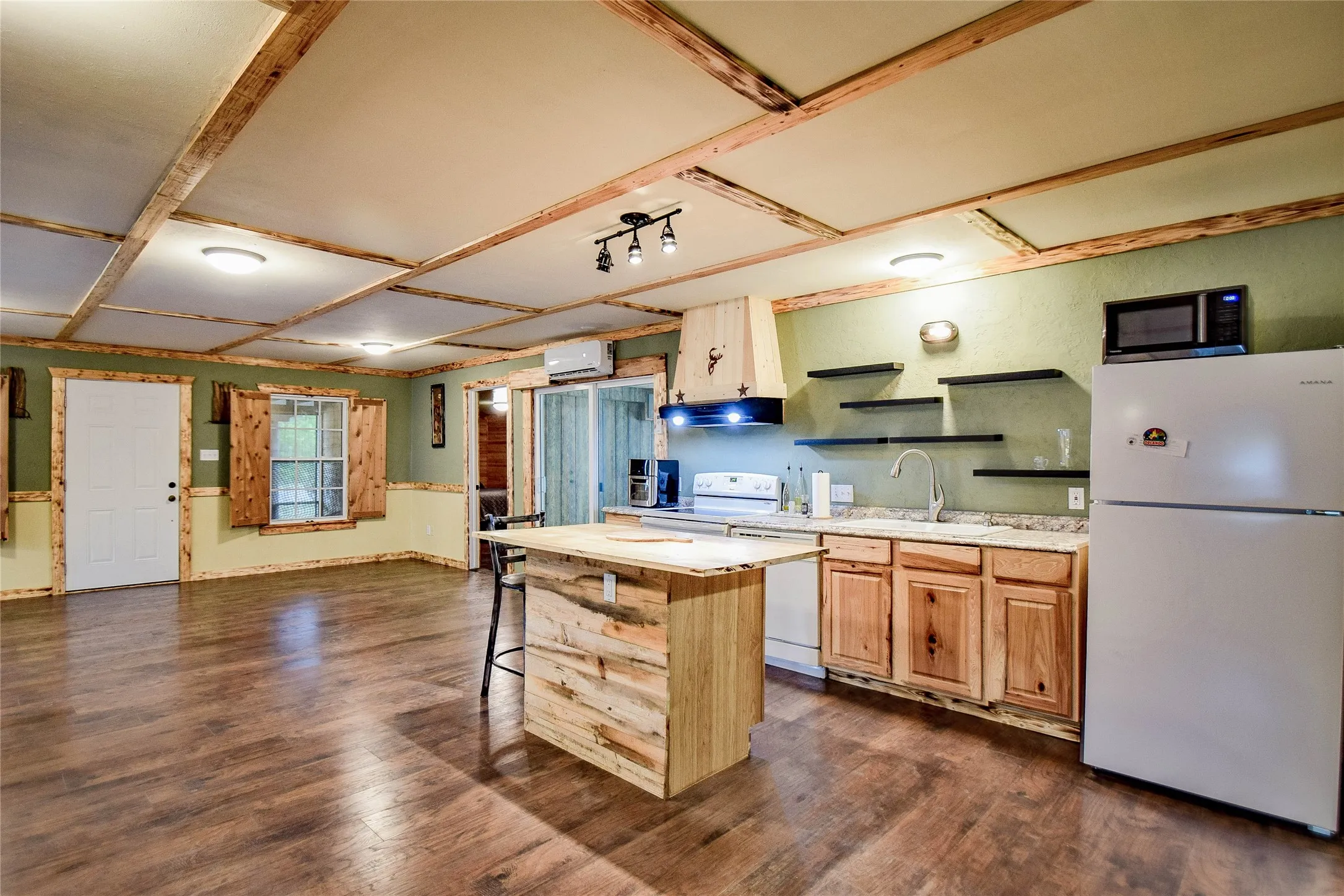 Kitchen space with beautiful wood cabinets, wood kitchen island, hand crafted vent hood, and plenty of good lighting. All appliances stay.
