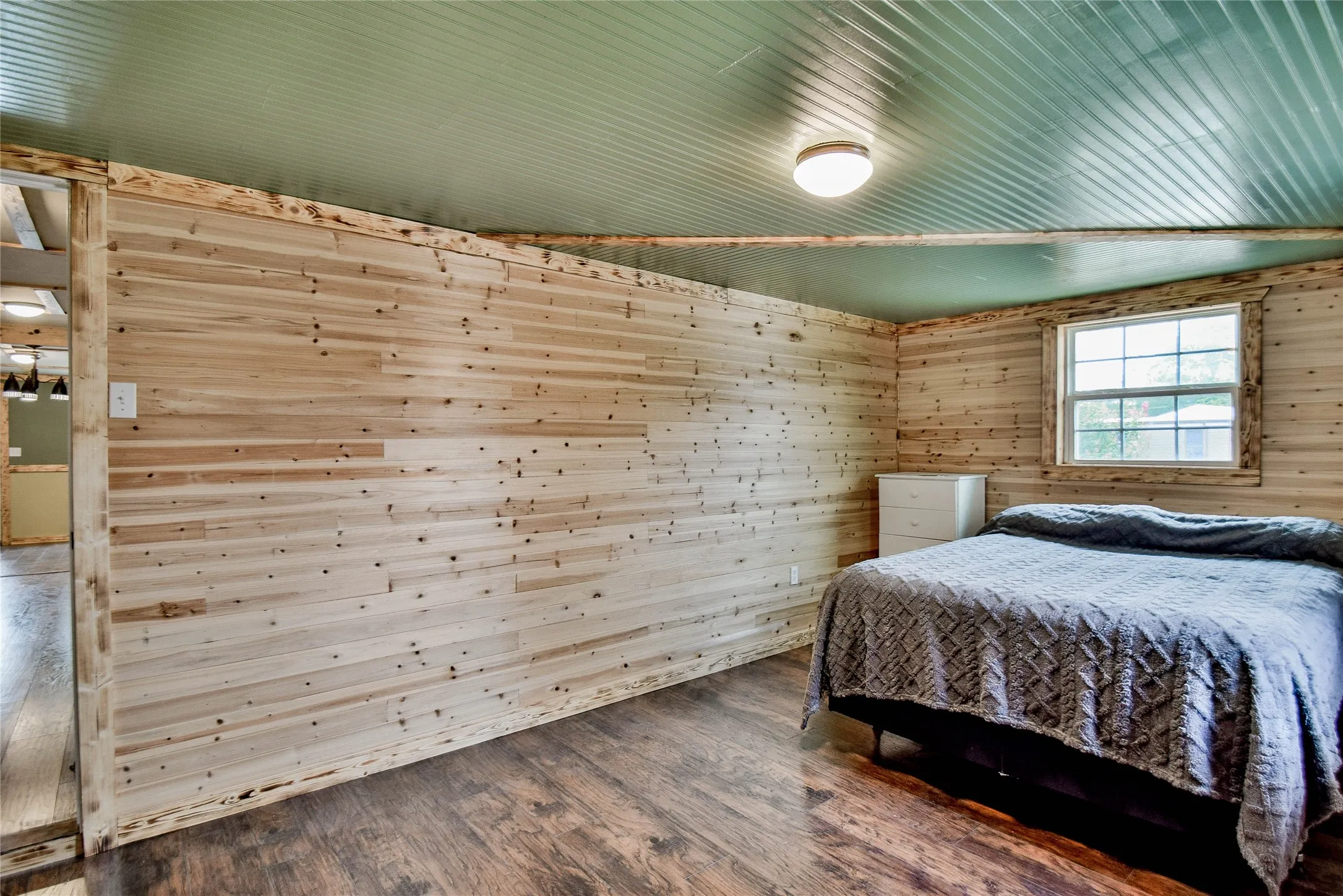 Front Bedroom with beautiful wood walls and wood-type laminate flooring makes a cozy retreat for guests and family.