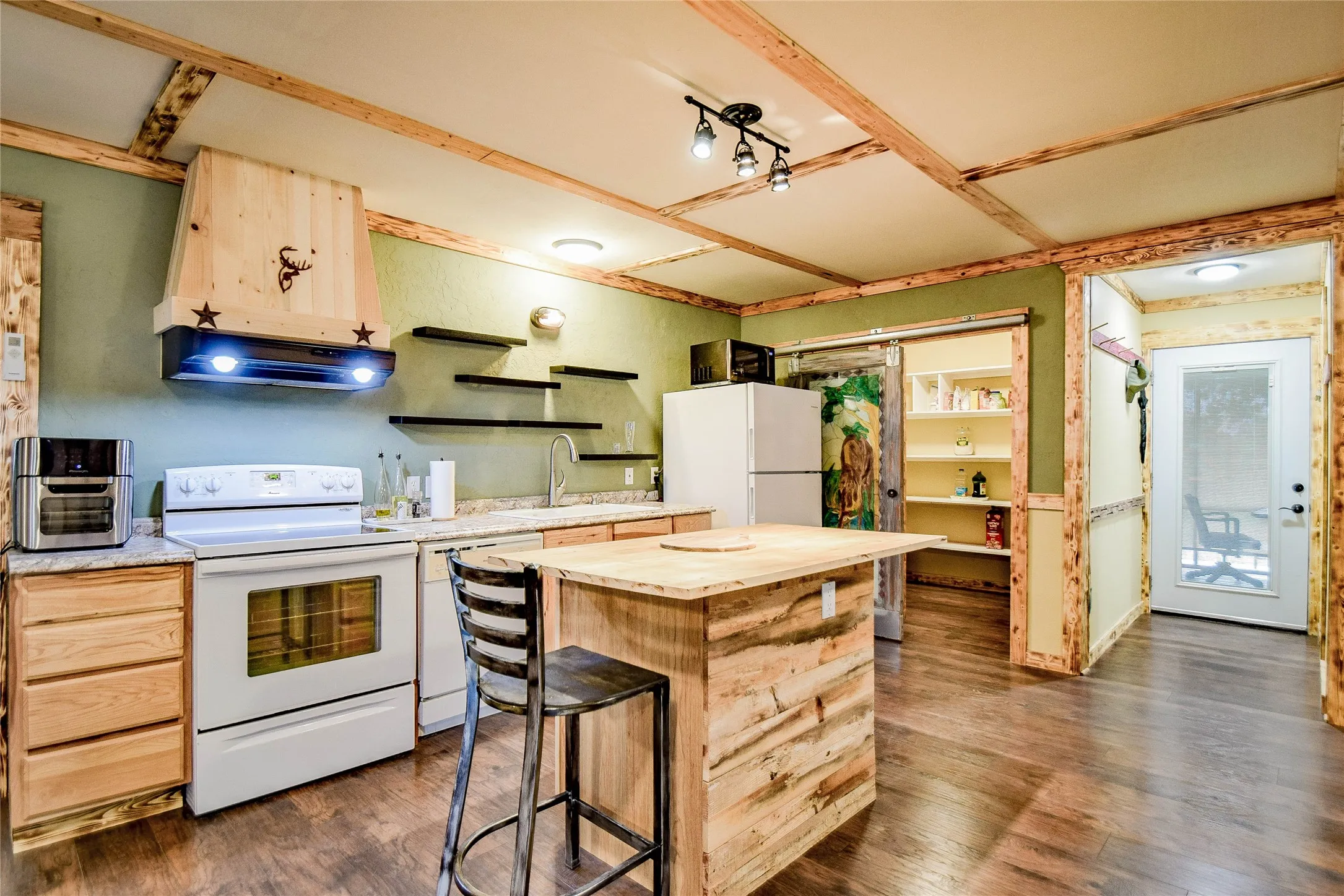 Great kitchen featuring beautiful wood cabinets and kitchen island along with hand-made vent hood. Huge walk-in pantry with hand painted sliding doors.