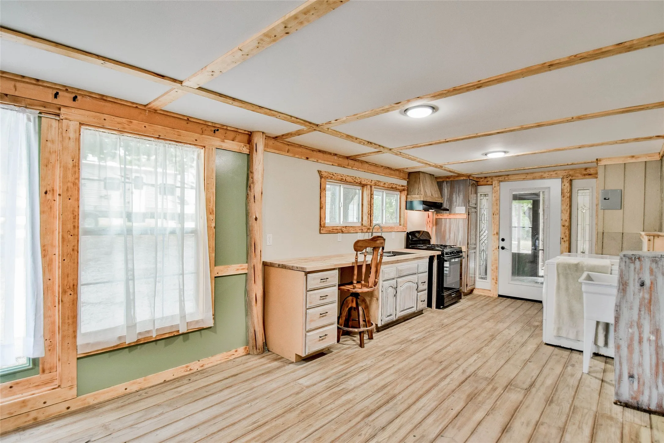 Rare Second Kitchen with light wood flooring, sink, black gas range oven, wall chimney exhaust hood, and great beamed ceiling allows for cooking those special dishes away from the main house!