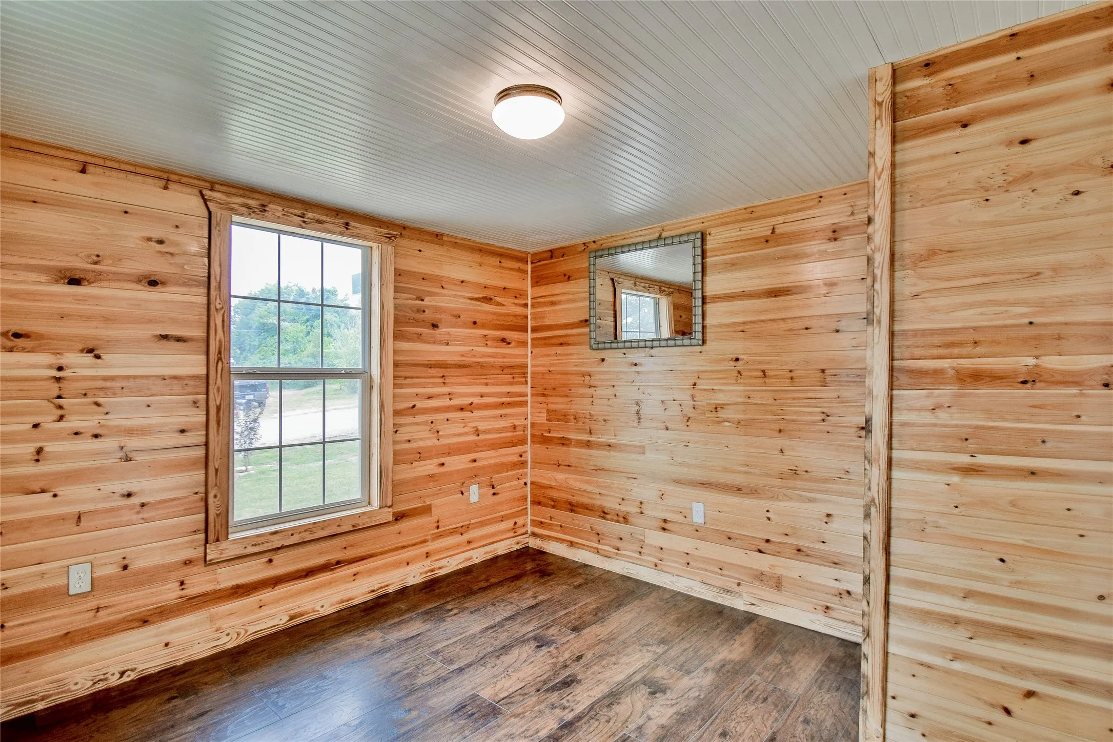 Guest bedroom featuring beautiful knotty pine paneling, B Board ceiling, and easy care wood-look laminate flooring.
