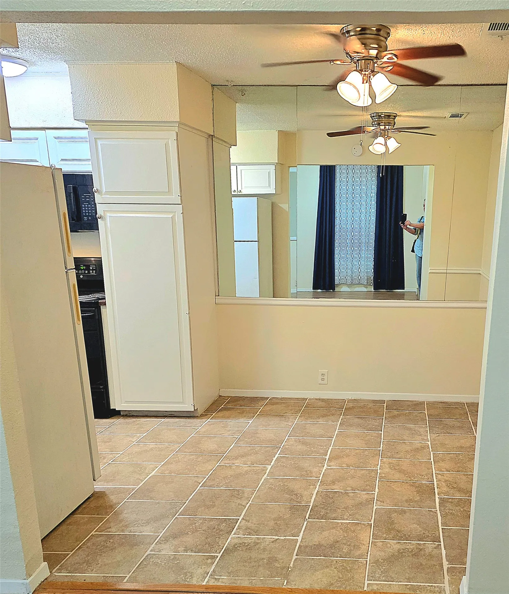 Dining area features chair rail molding with mirror above on one wall, a ceiling fan, and neutral ceramic tile flooring.