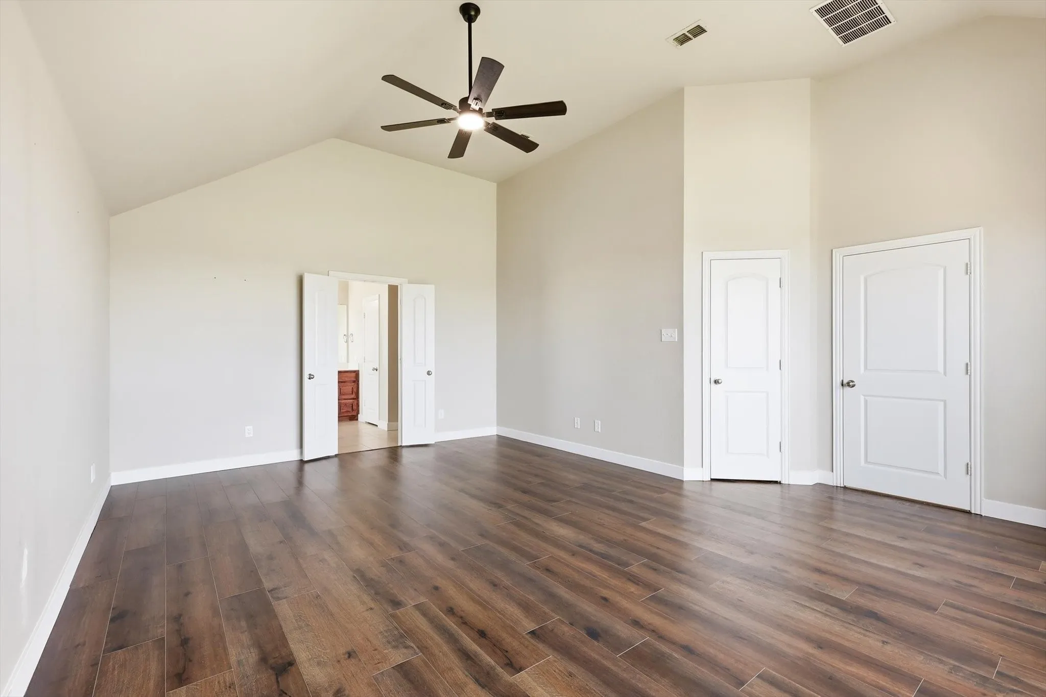 Large primary bedroom with natural light, high ceilings, lvp flooring, ensuite bathroom and walk in closet