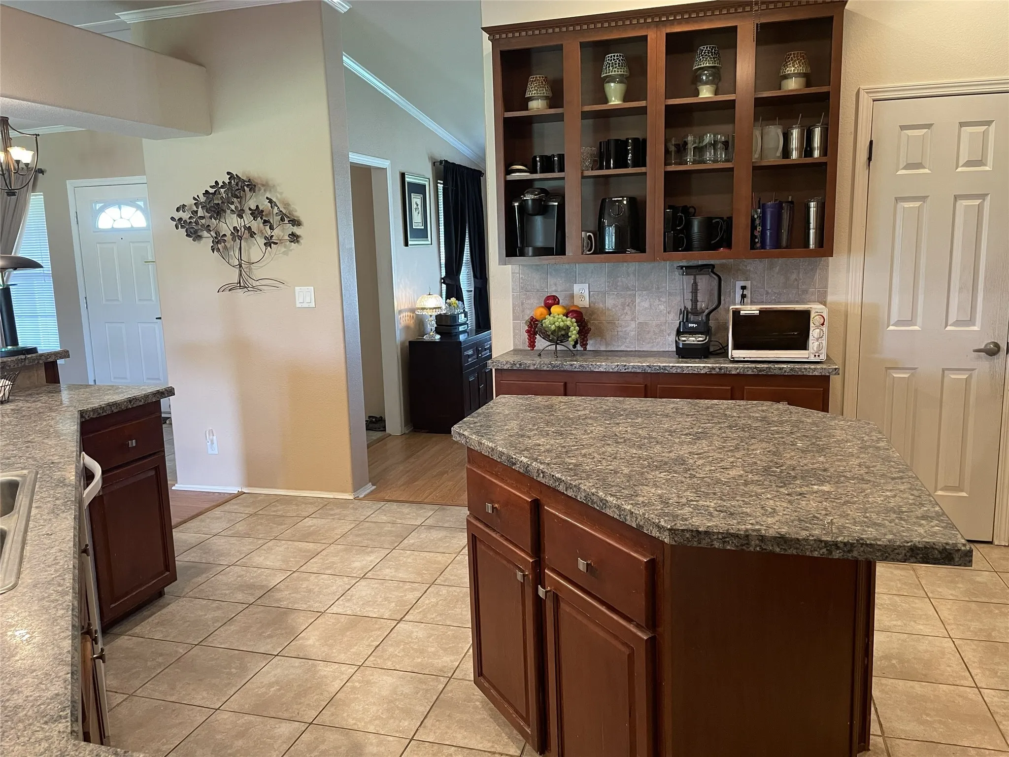 Spacious kitchen featuring an island, upper open cabinetry, a pantry on the right
