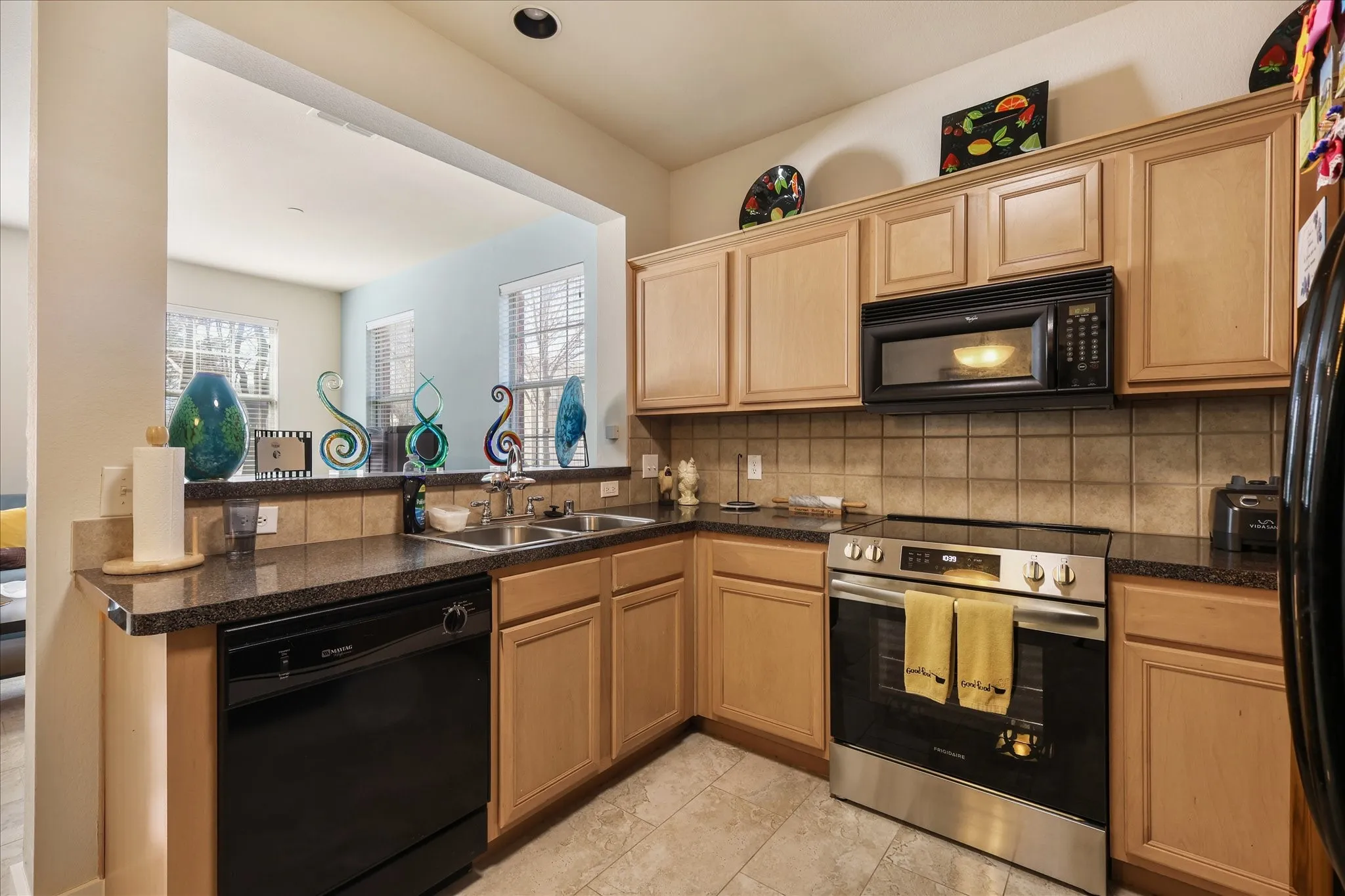 Kitchen featuring black appliances, dark countertops, a peninsula, and decorative backsplash