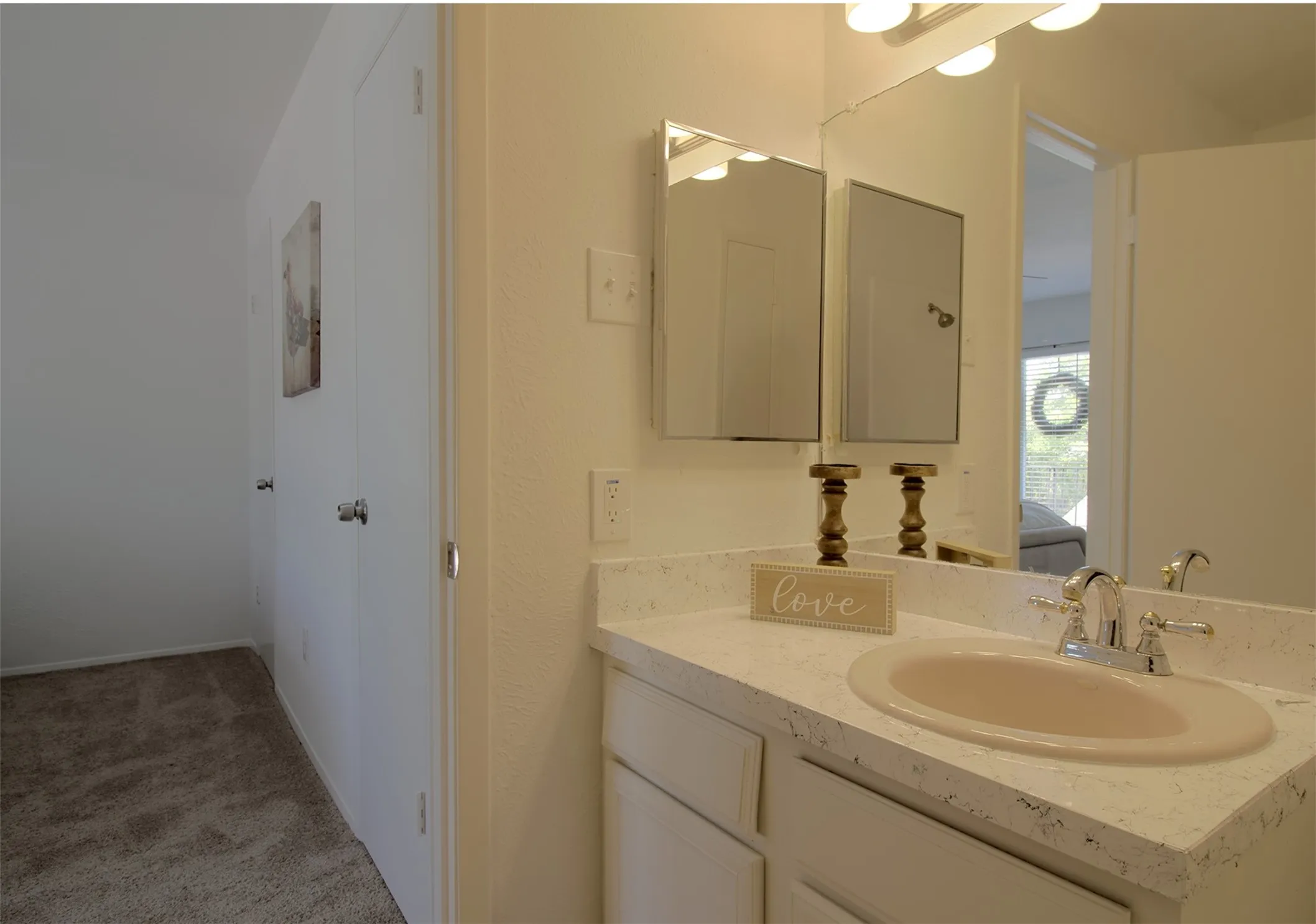 Ensuite bathroom with vanity and light colored carpet