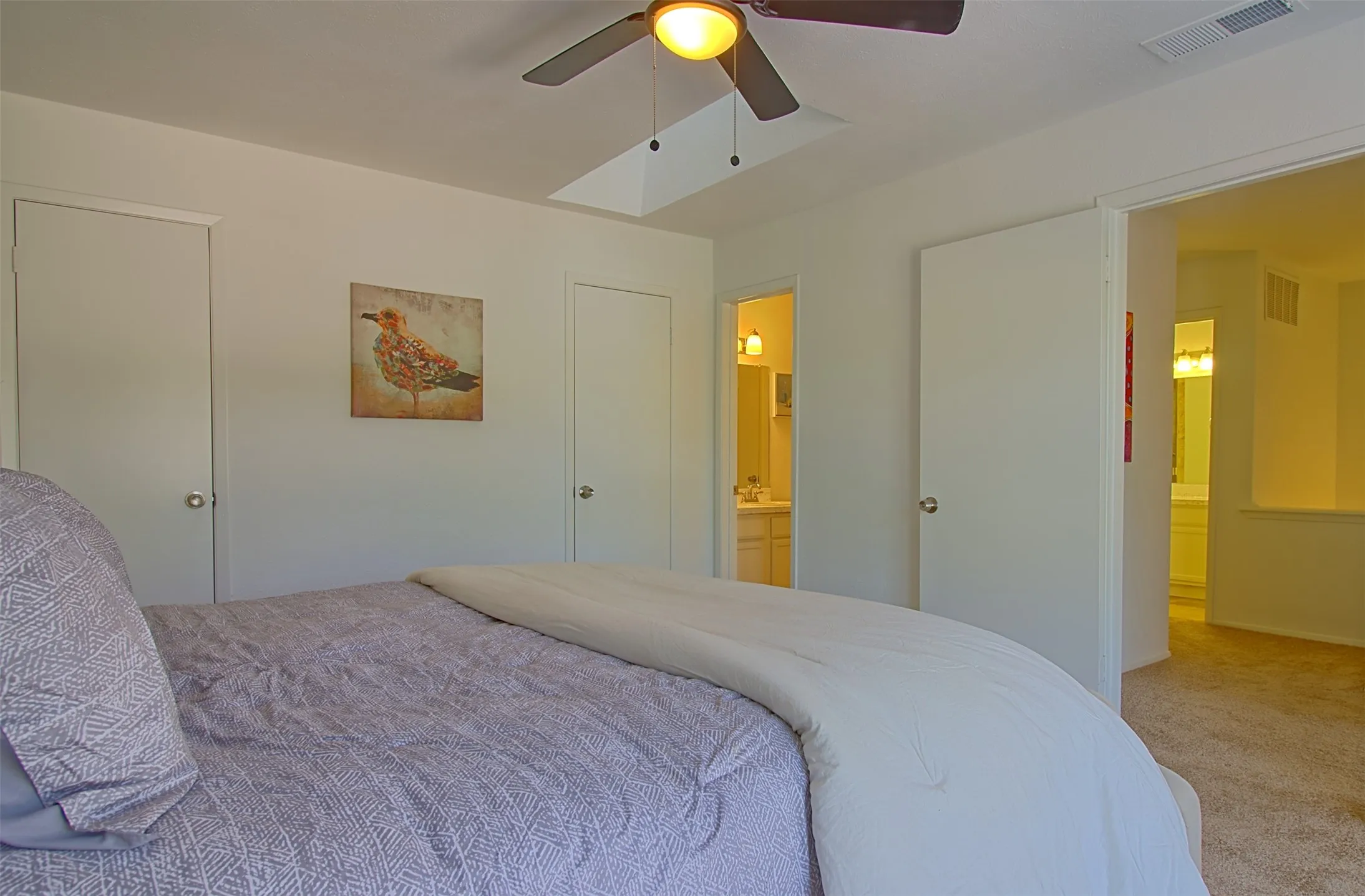 Bedroom with carpet, ceiling fan, and connected bathroom