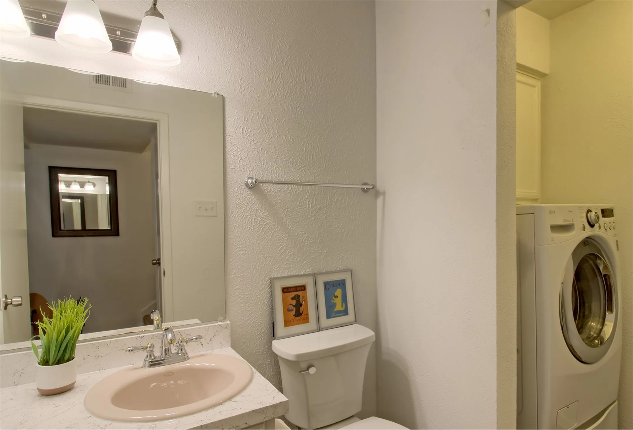 Half bath featuring a textured wall, washer / dryer, and vanity