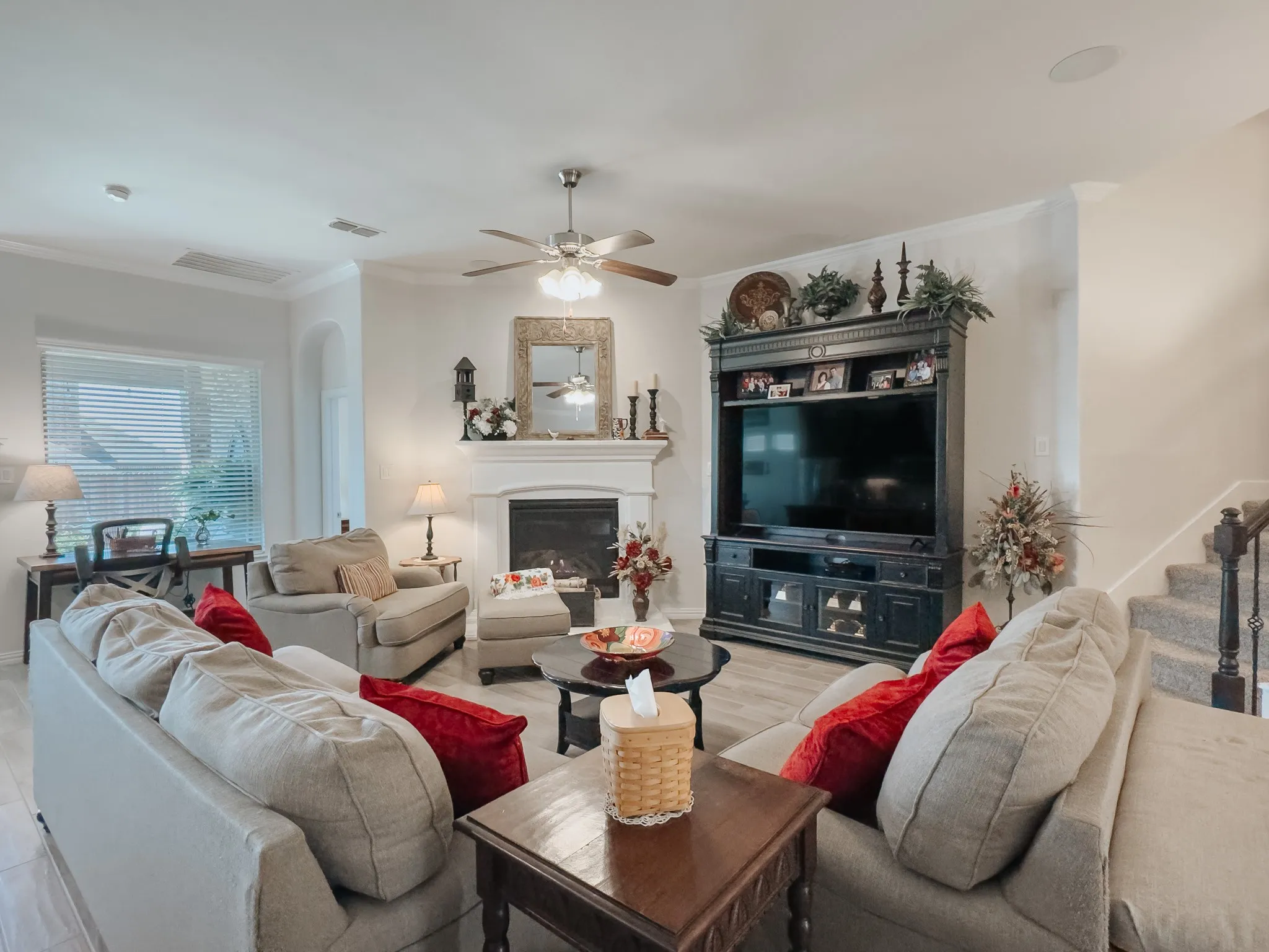 Living room with ceiling fan, crown molding, and gas logs in fireplace