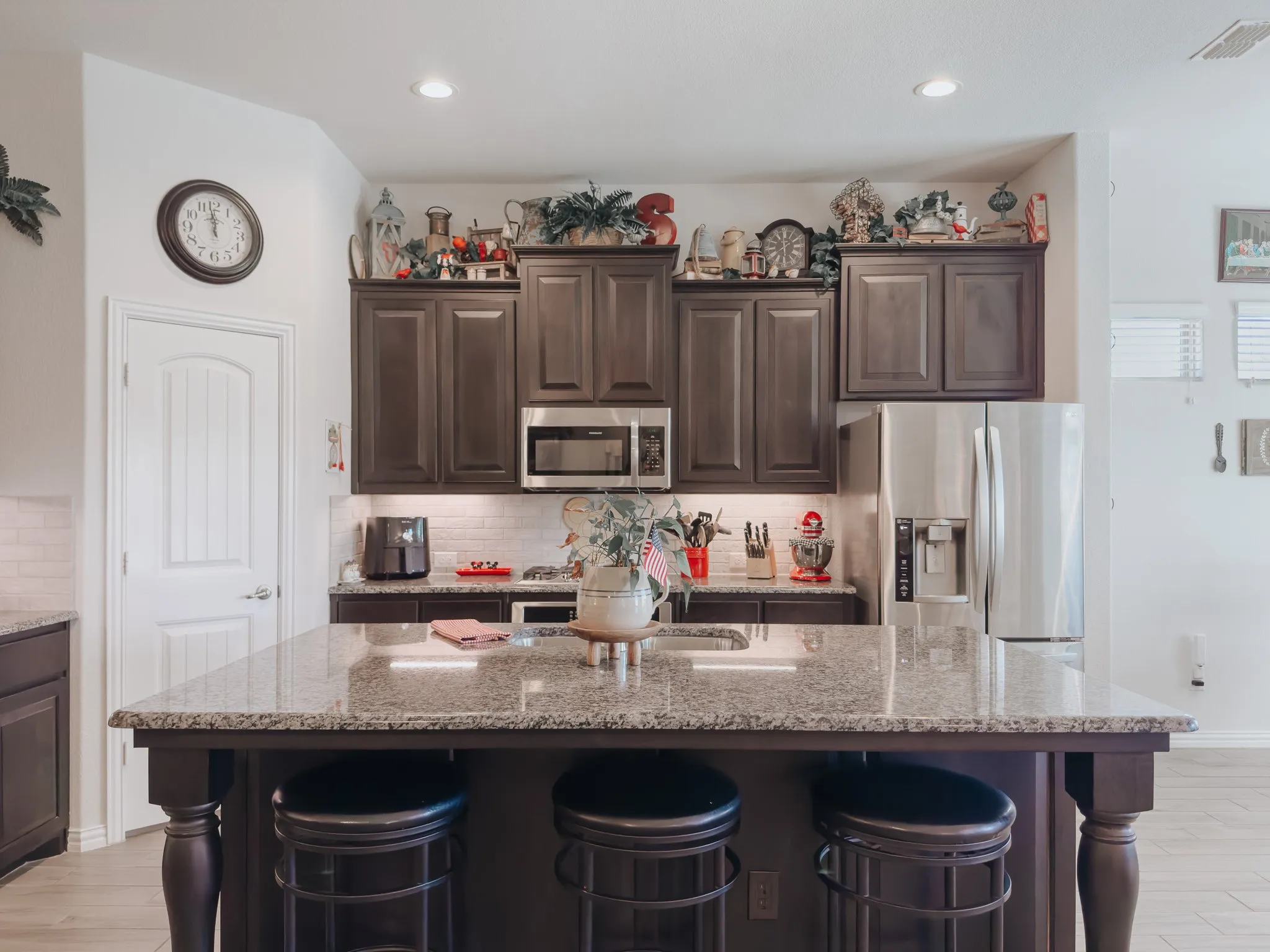 Kitchen with an island with sink, tasteful backsplash, a breakfast bar area, appliances with stainless steel finishes, and light stone counters