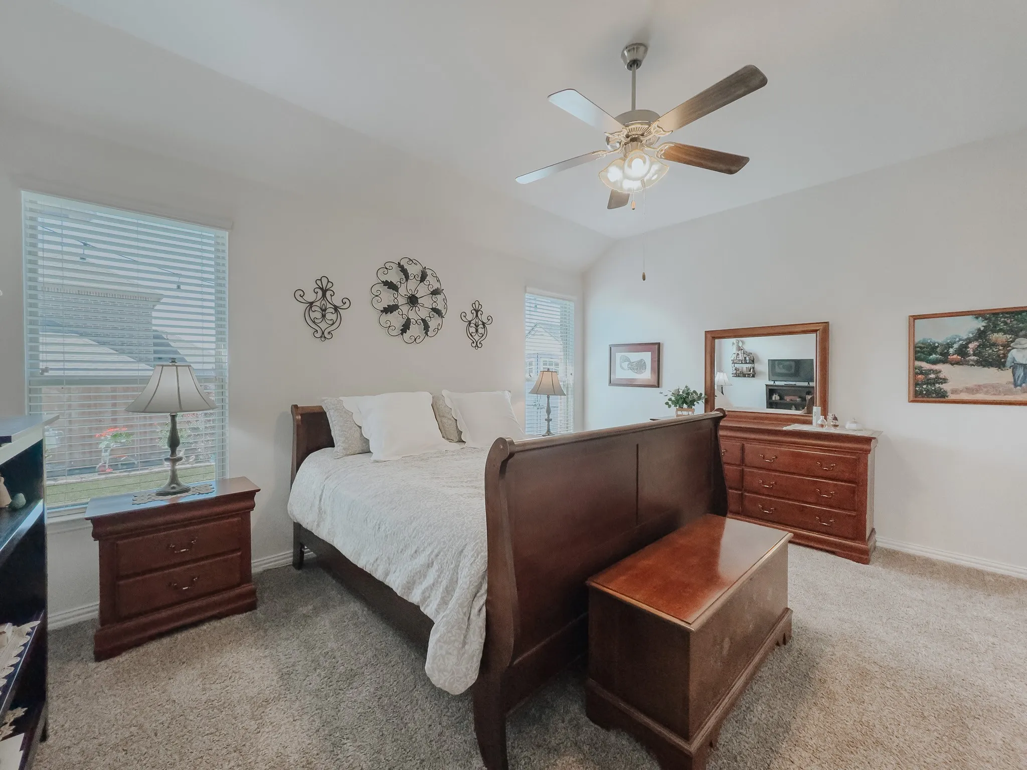 Carpeted primary bedroom featuring ceiling fan and lofted ceiling