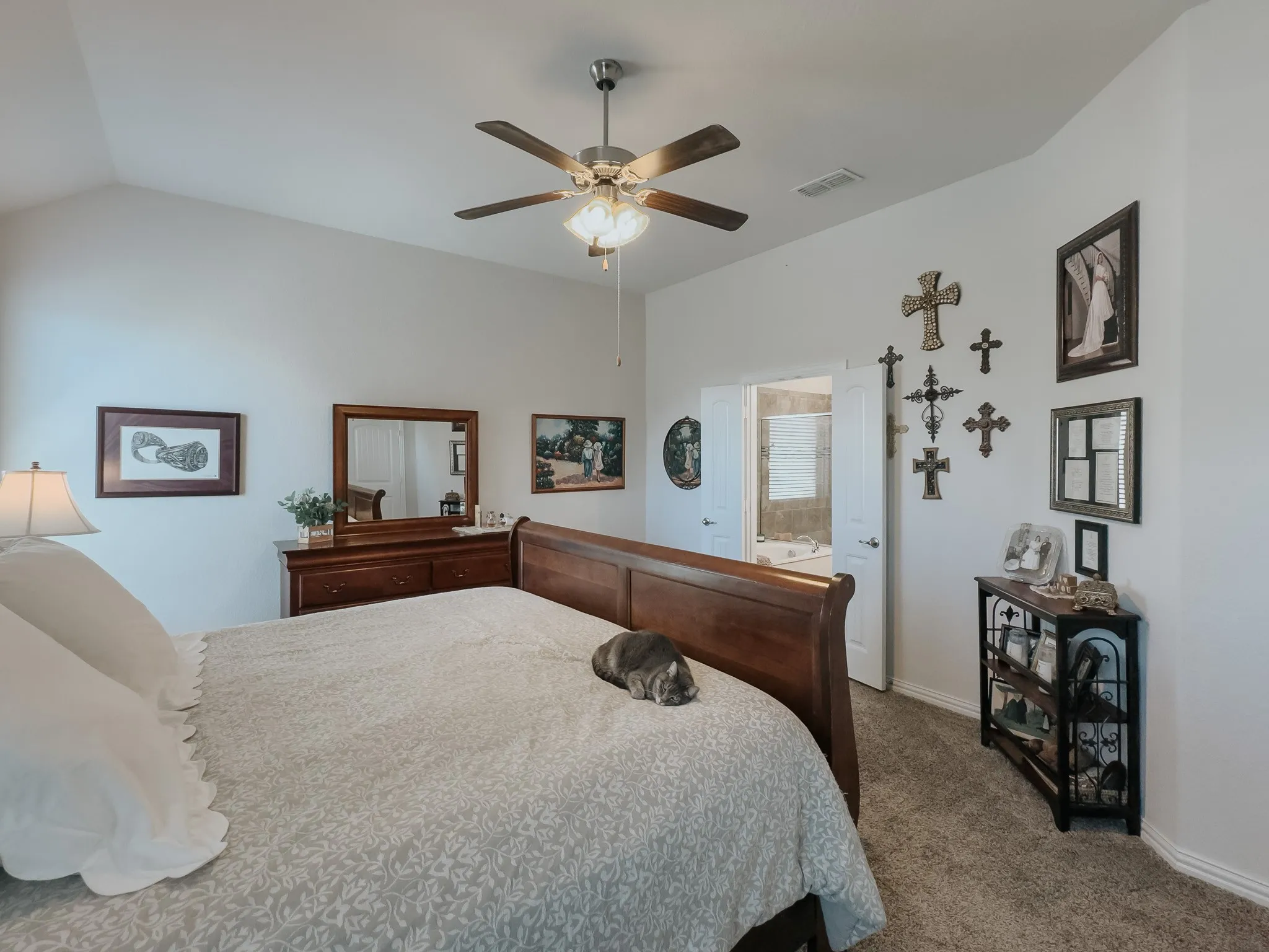 Bedroom with ensuite bath, ceiling fan, and light colored carpet