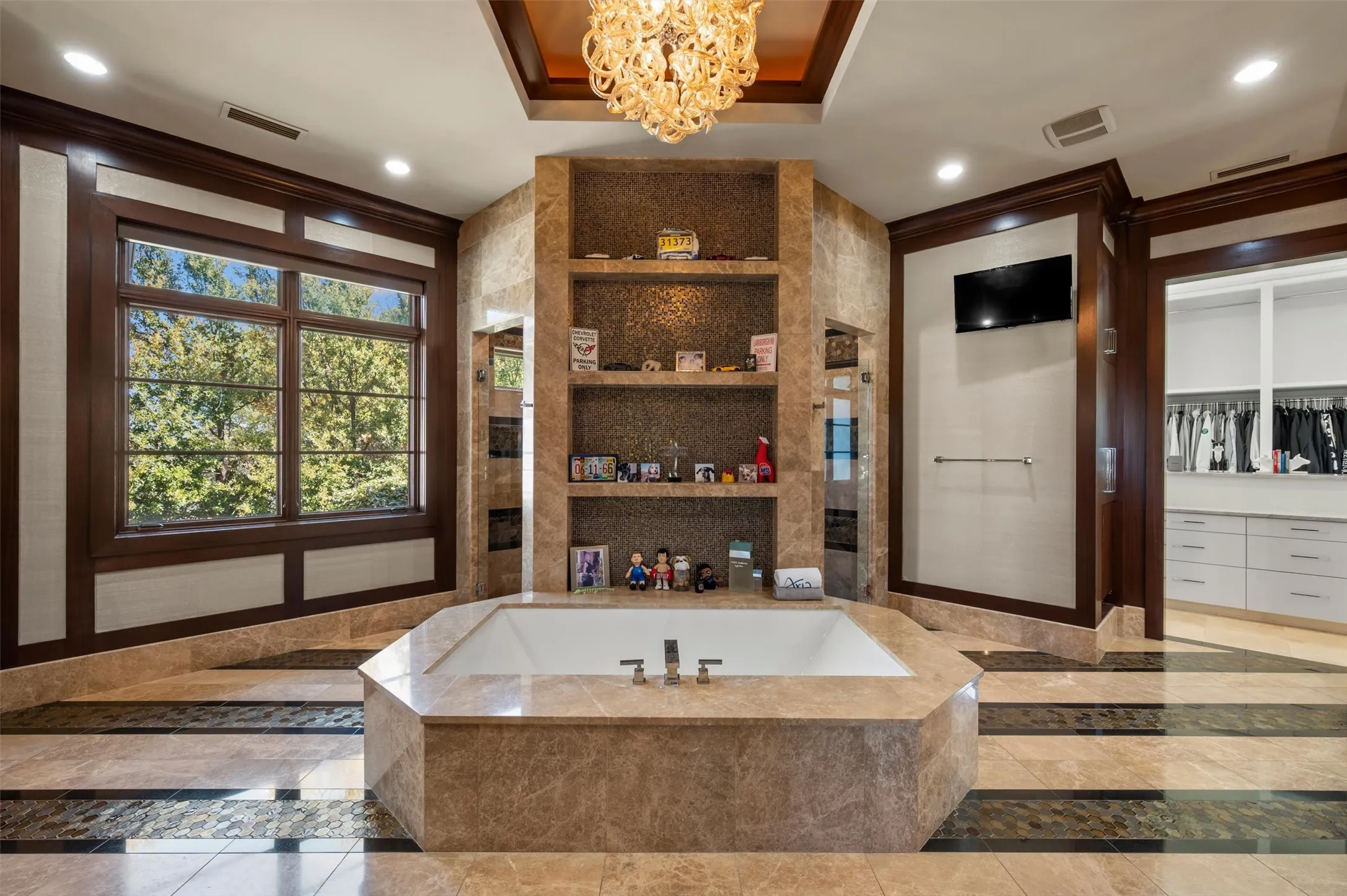 Primary Bathroom featuring inlaid floor details, a chandelier, a bubble tub, built in shelves, raised ceiling and dual vanities