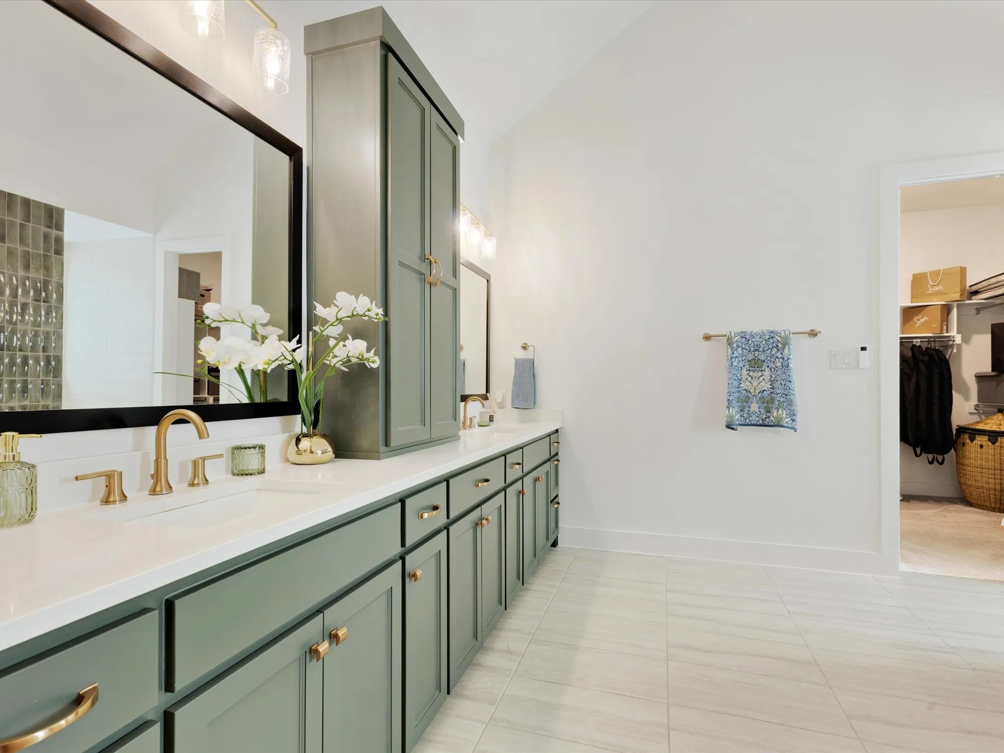  Primary bathroom with double vanity, a walk in closet, light tile patterned flooring, and lofted ceiling