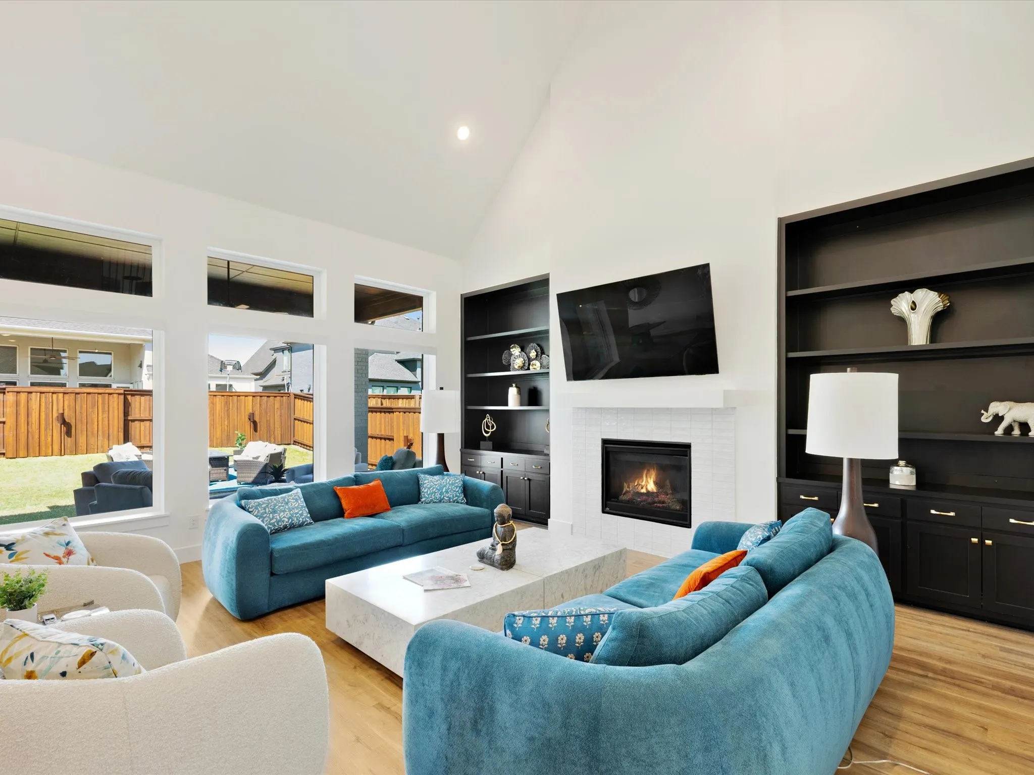 Living room featuring a tiled fireplace, light wood-style flooring, vaulted ceiling, built in features, and recessed lighting