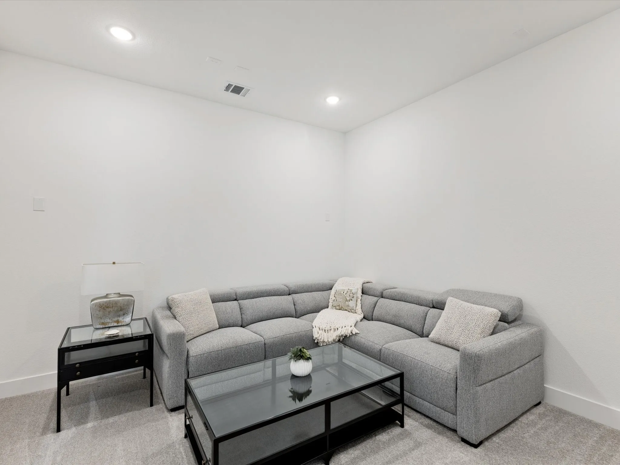 Downstairs media room with light colored carpet and recessed lighting