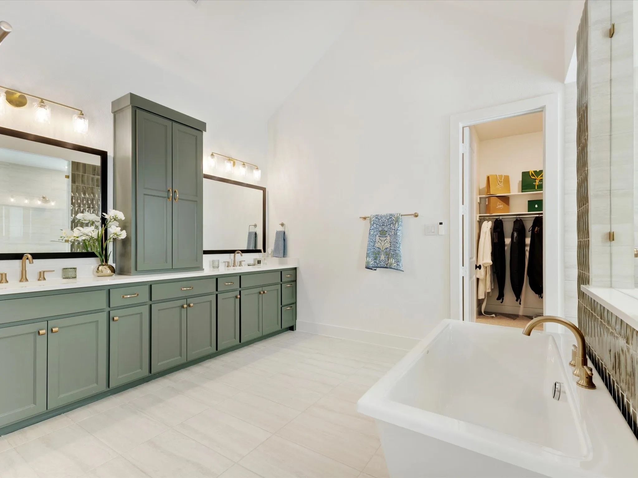  Primary Bathroom with double vanity, a freestanding tub, lofted ceiling, tiled shower, and a walk in closet