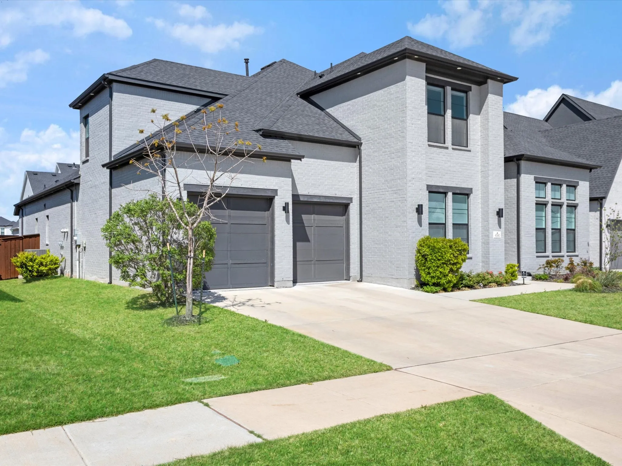 View of front of house featuring brick siding, driveway, an attached garage, a front yard, and a shingled roof