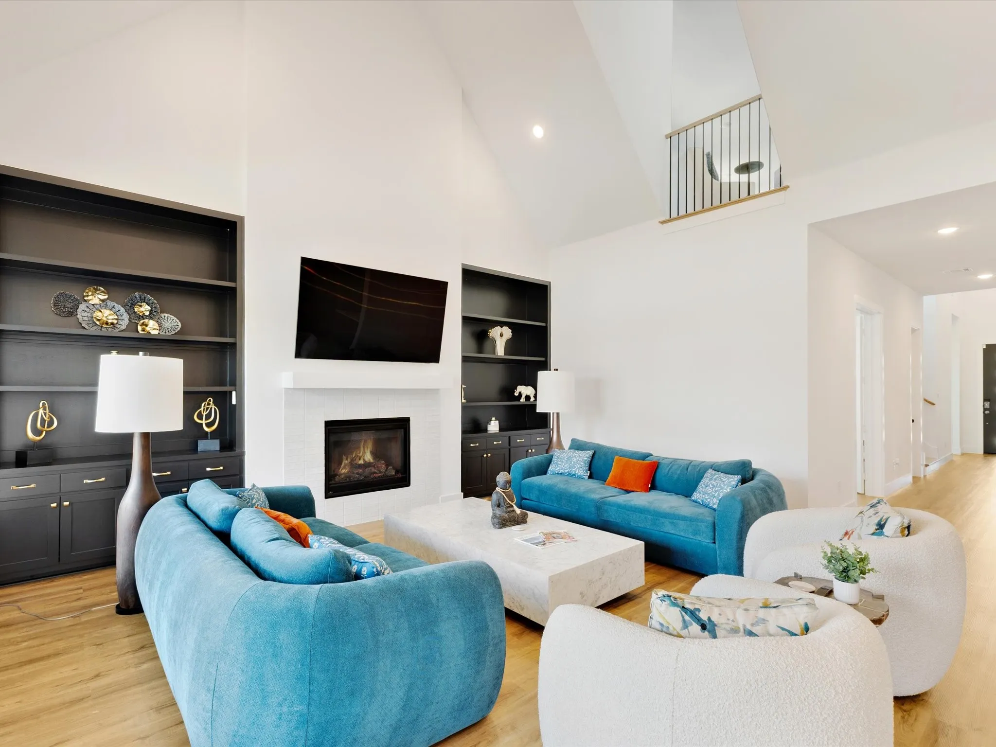 Living room featuring light wood-style floors, built in features, a glass covered fireplace, lofted ceiling, and recessed lighting