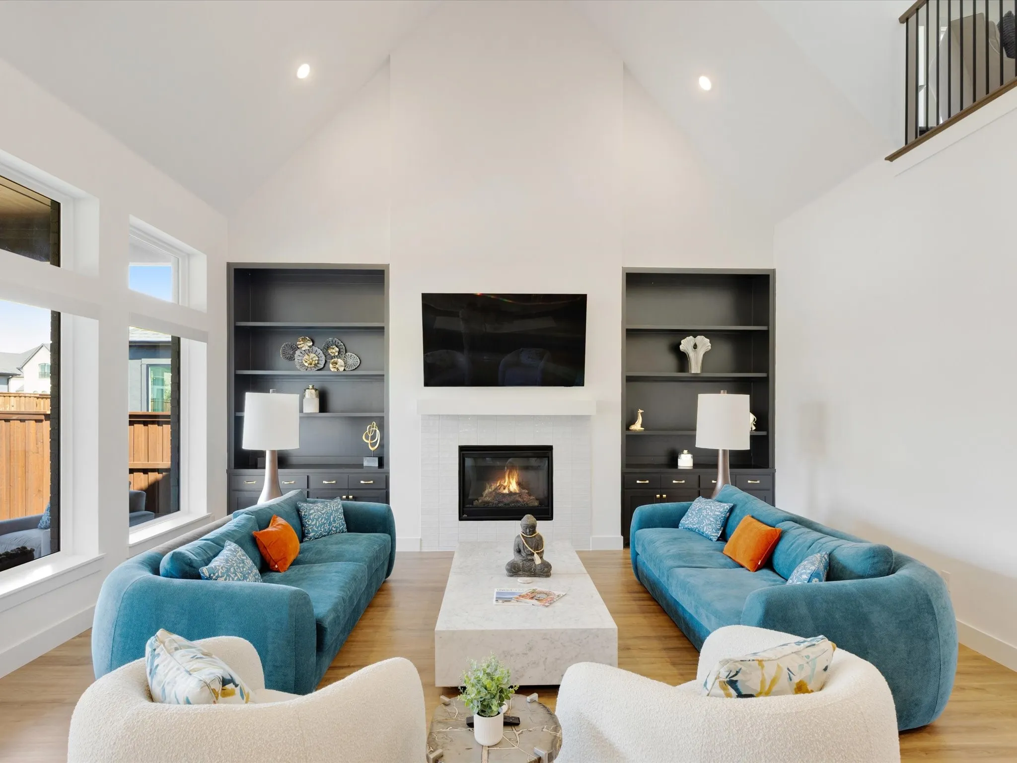 Living room featuring built in features, light wood finished floors, a tiled fireplace, vaulted ceiling, and recessed lighting